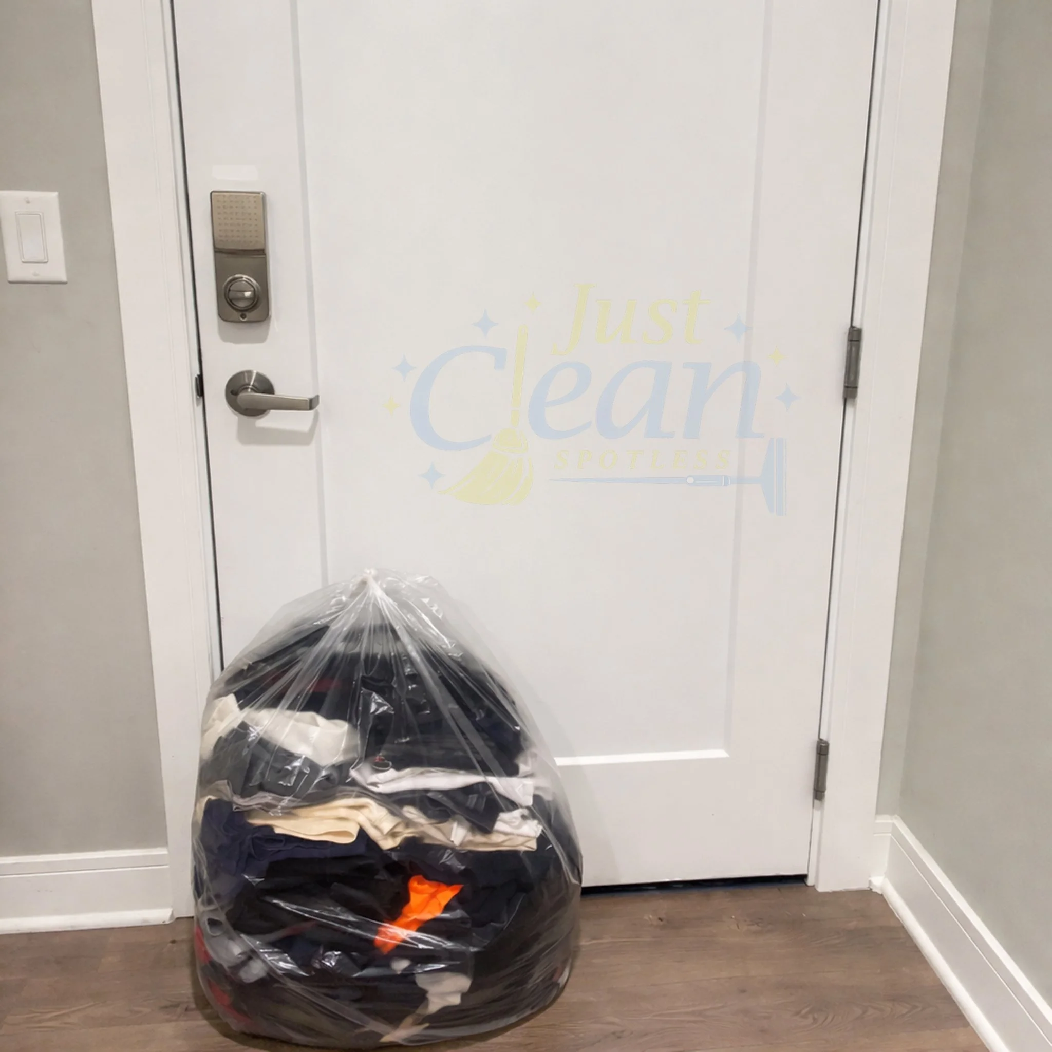 A laundry room closet with a white door, electronic lock, and a pile of laundry in a black plastic bag on the floor.
