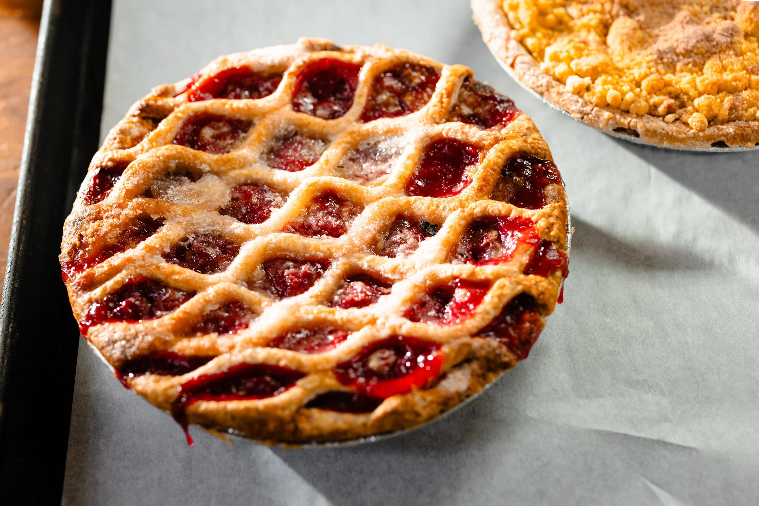Cherry pie with a lattice crust on a baking sheet.