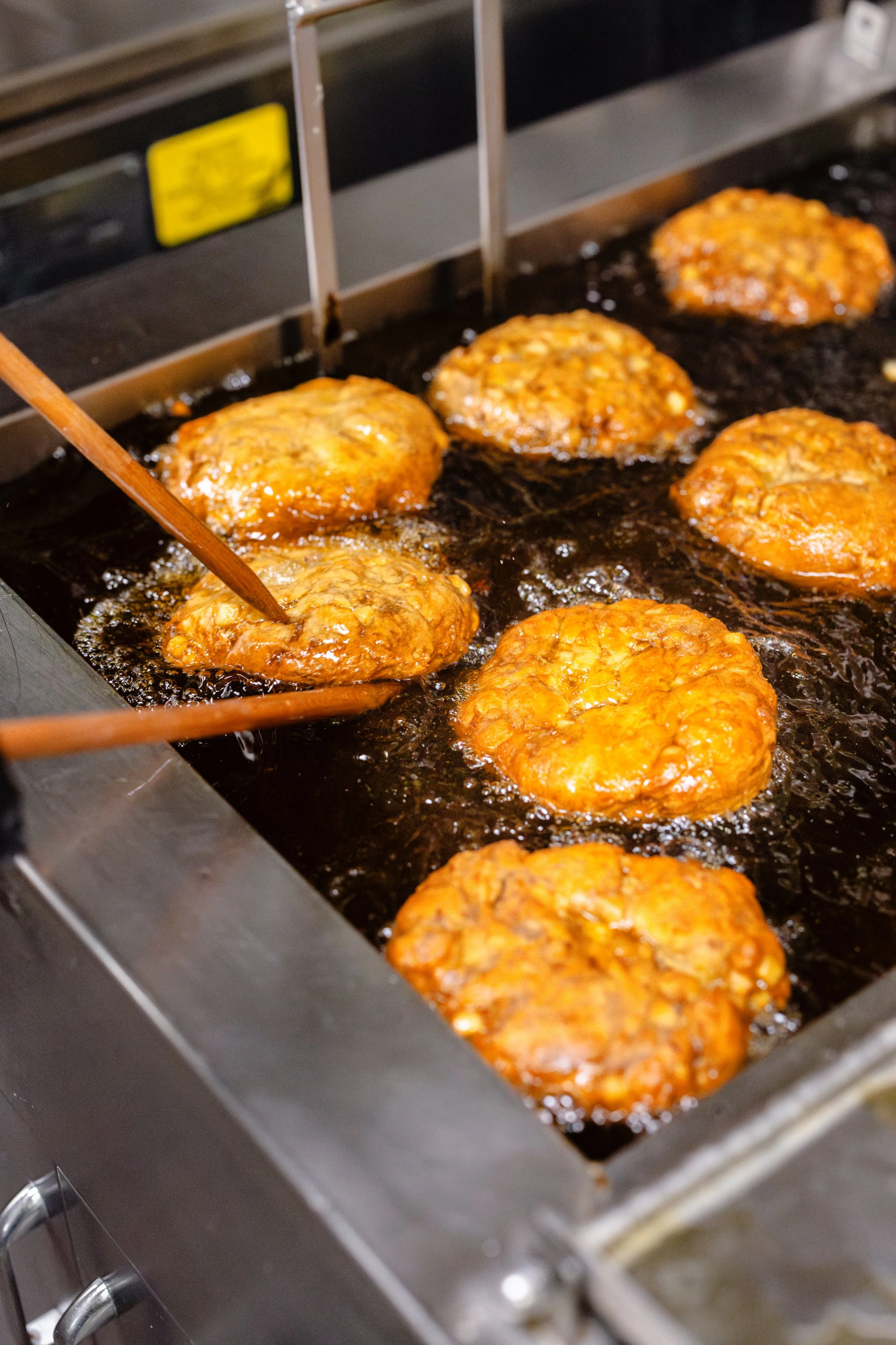Fried meat patties cooking in a deep fryer.