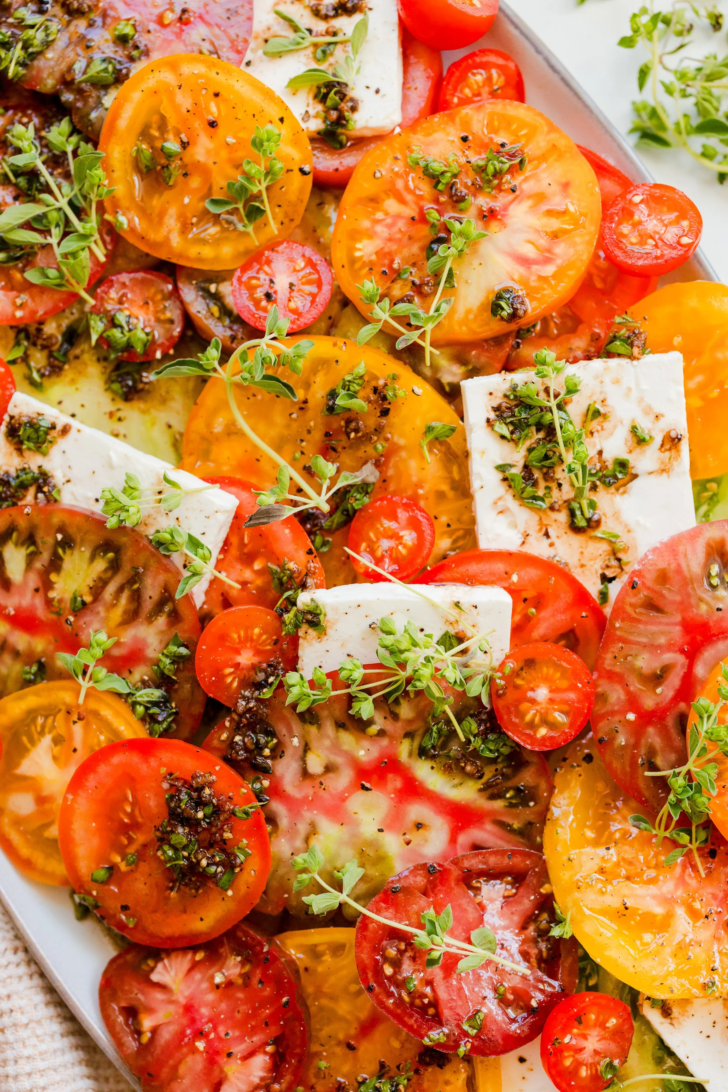 A colorful tomato and cheese salad with green herbs and black pepper.
