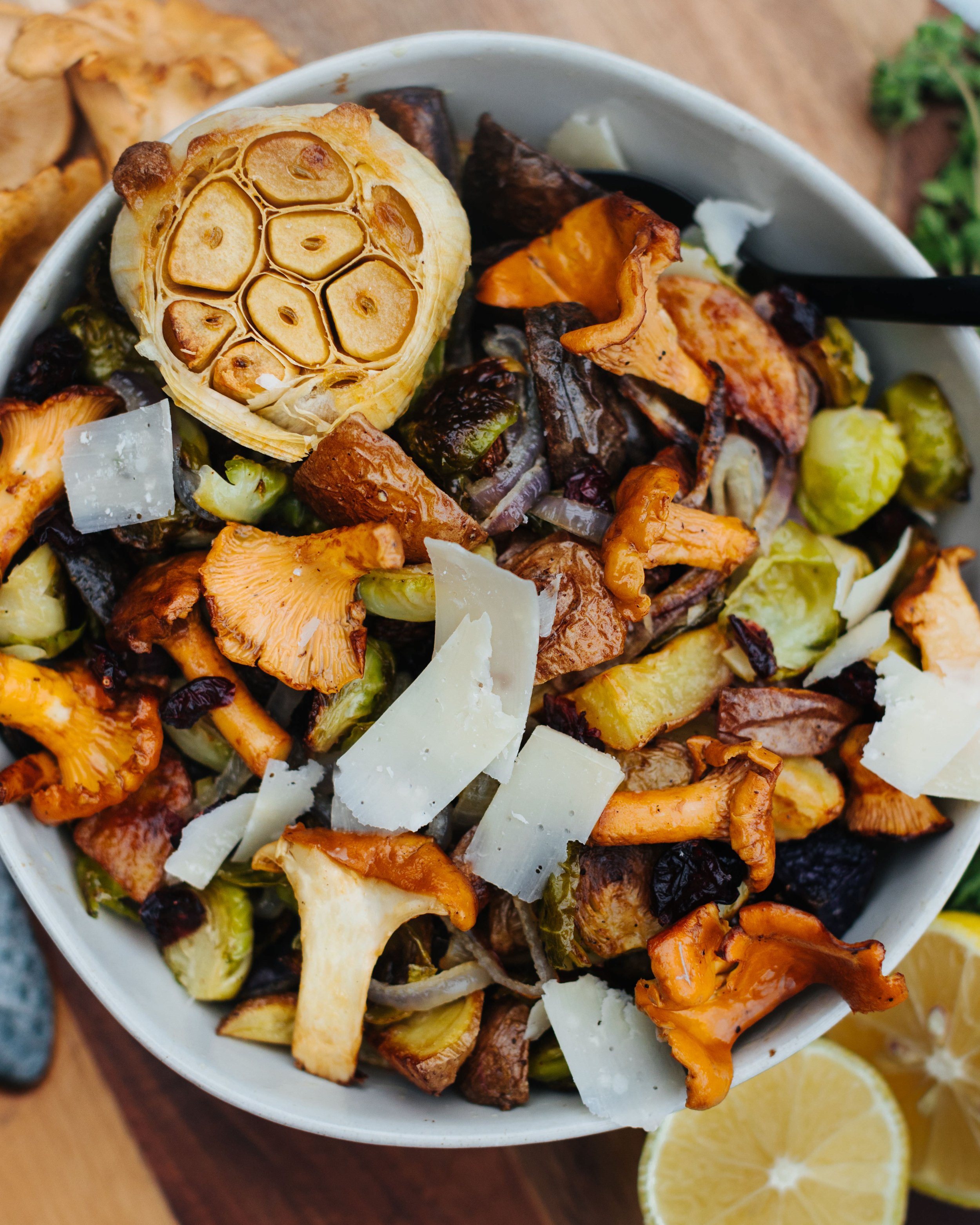 Roasted vegetable salad with garlic, shaved cheese, and lemon slices.