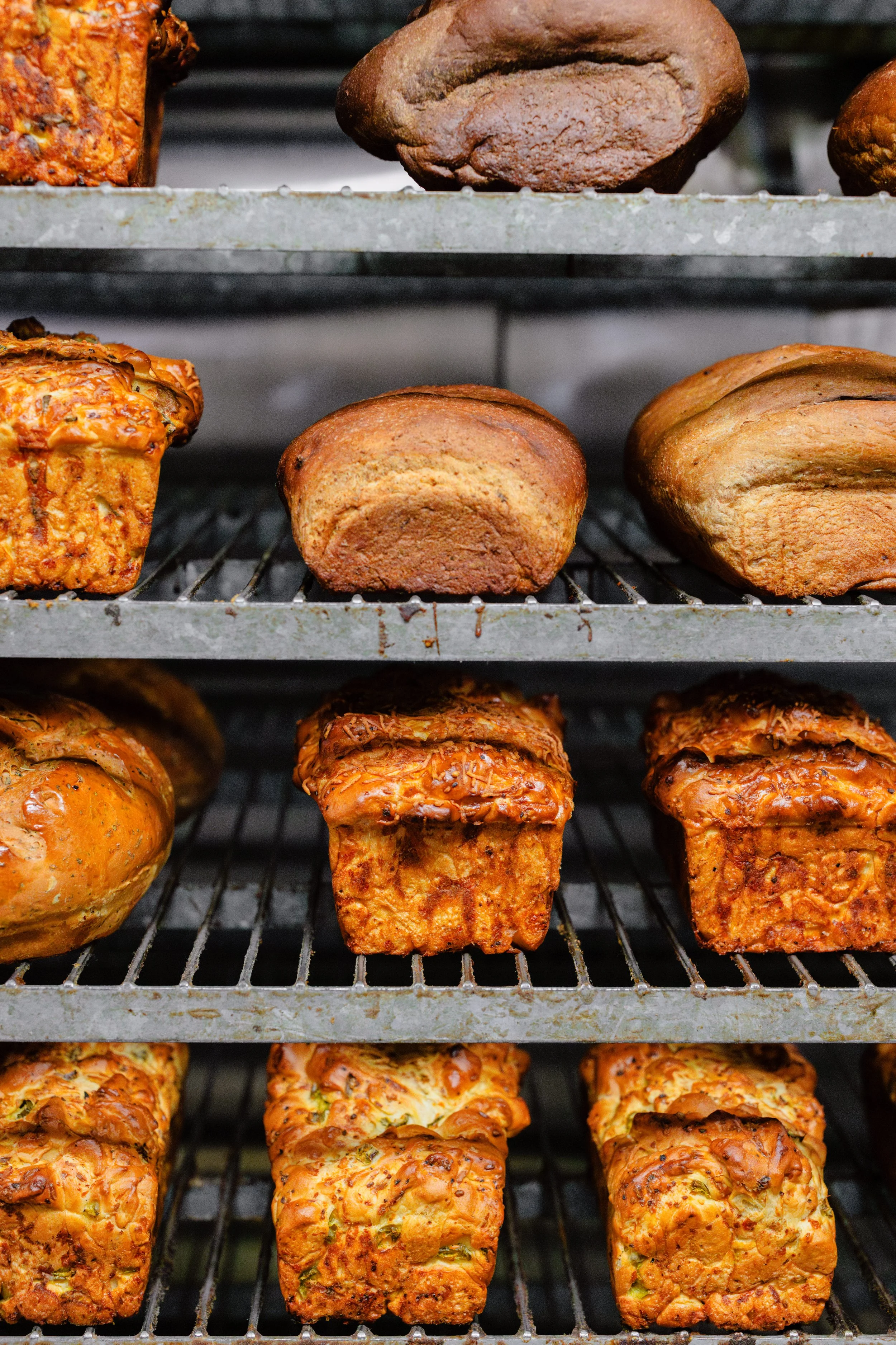 Baked goods on metal racks, including bread and pastry loaves with golden crusts.