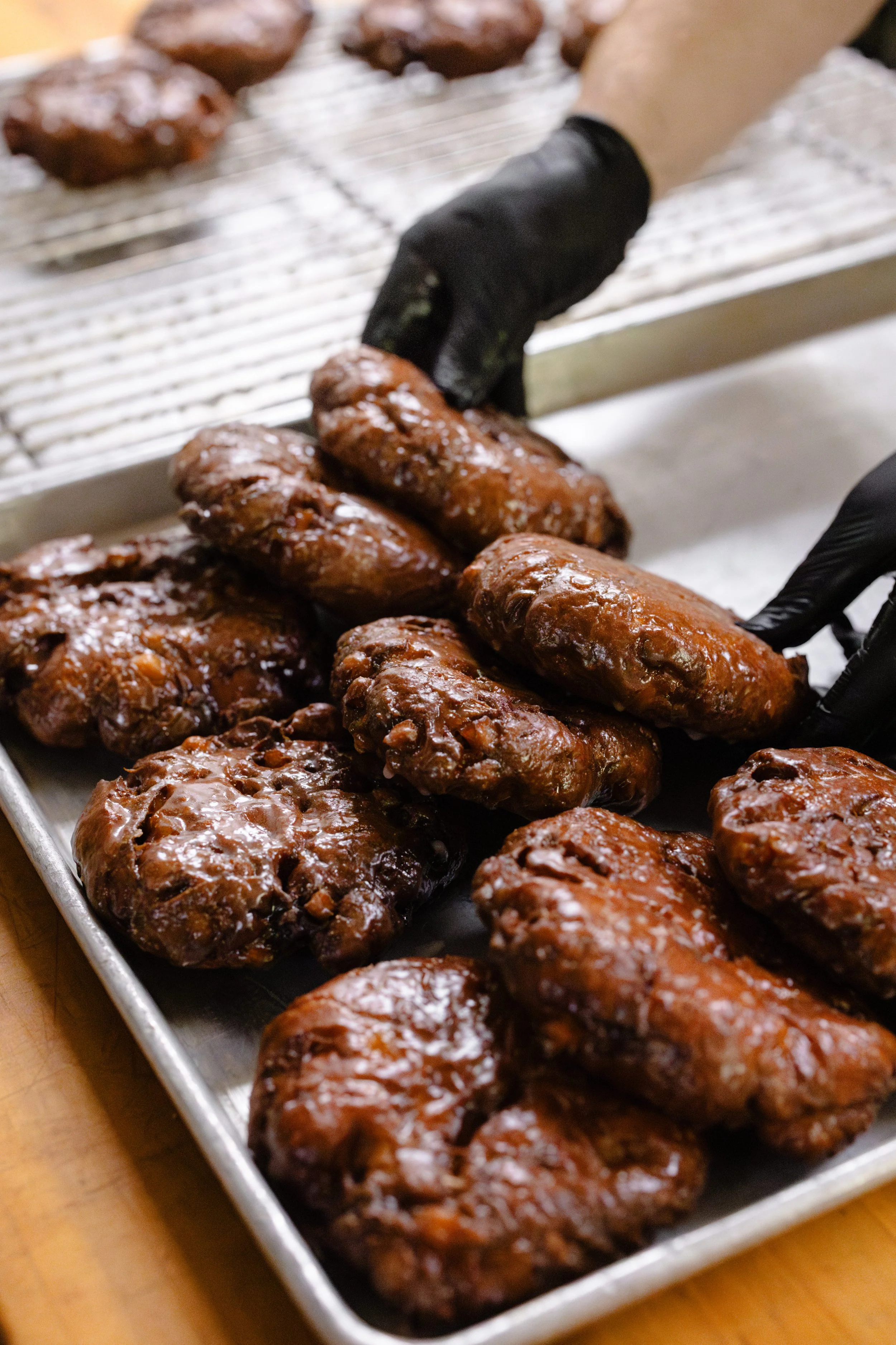 Gloved hand arranging glazed meatloaf on a baking sheet.