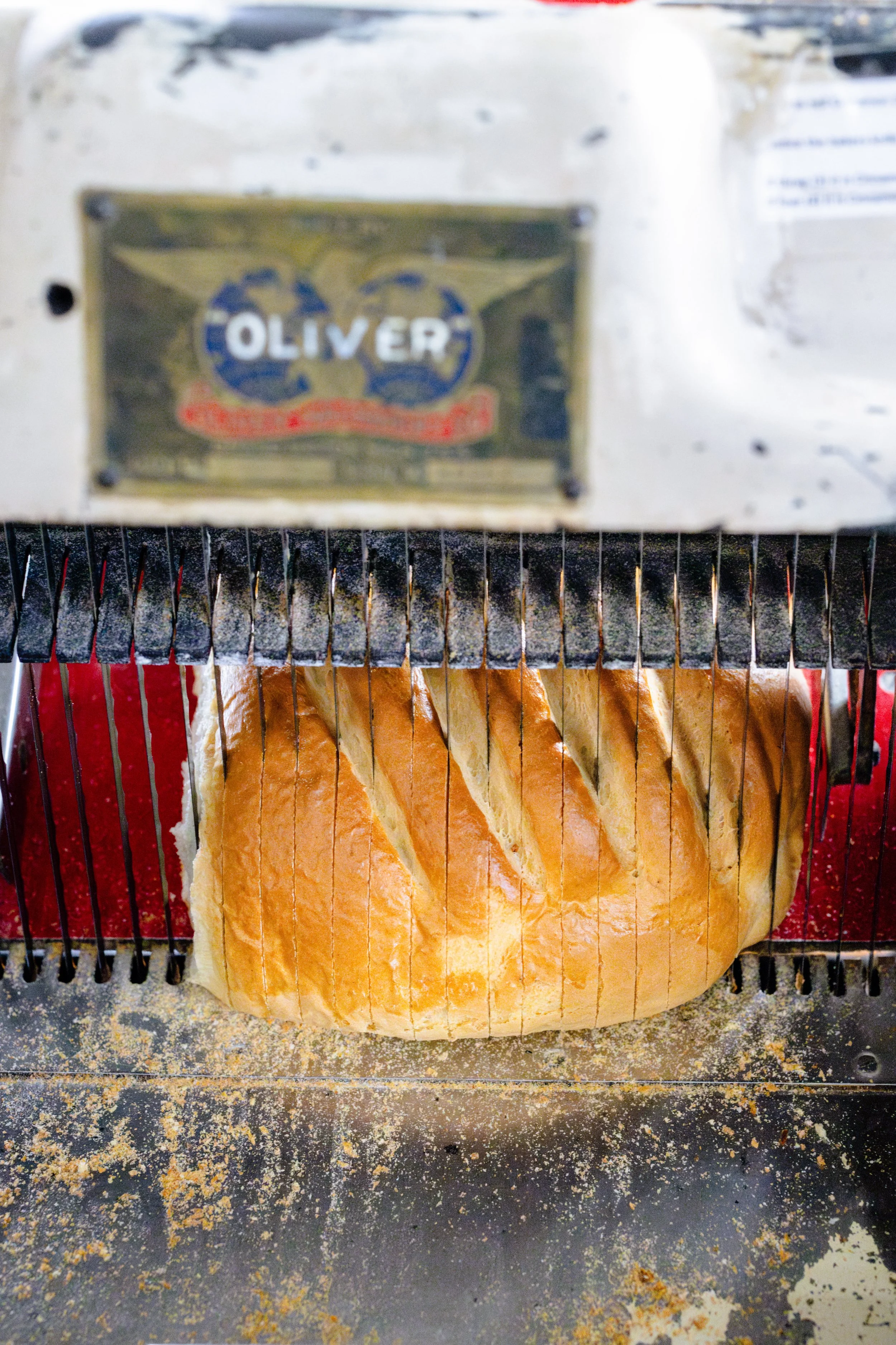 Sliced bread emerging from a bread slicing machine labeled 'Oliver'.
