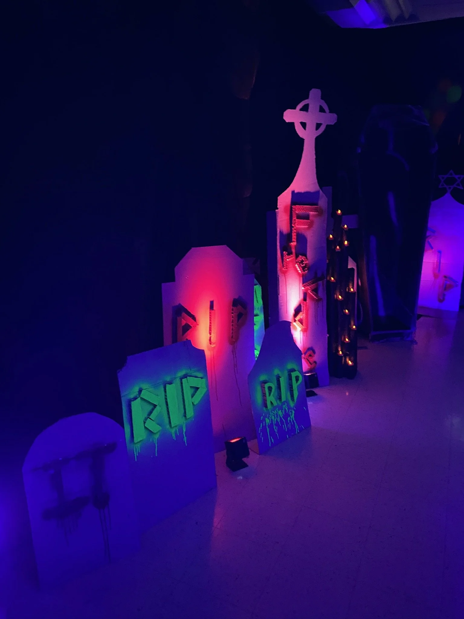 Decorative Halloween gravestones with 'RIP' in glow-in-the-dark paint and purple lighting.