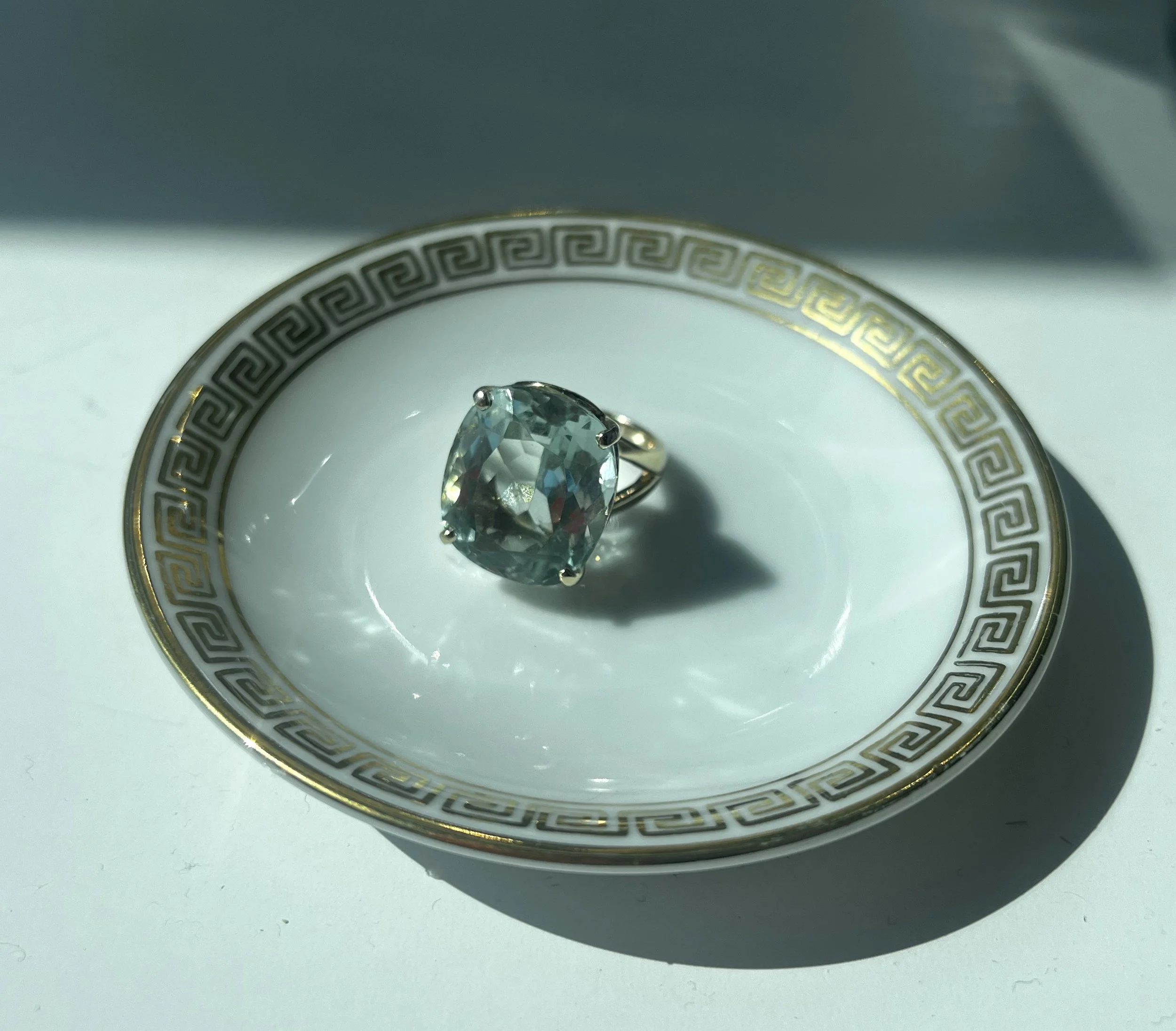 Vintage aquamarine ring in gold setting displayed on porcelain plate