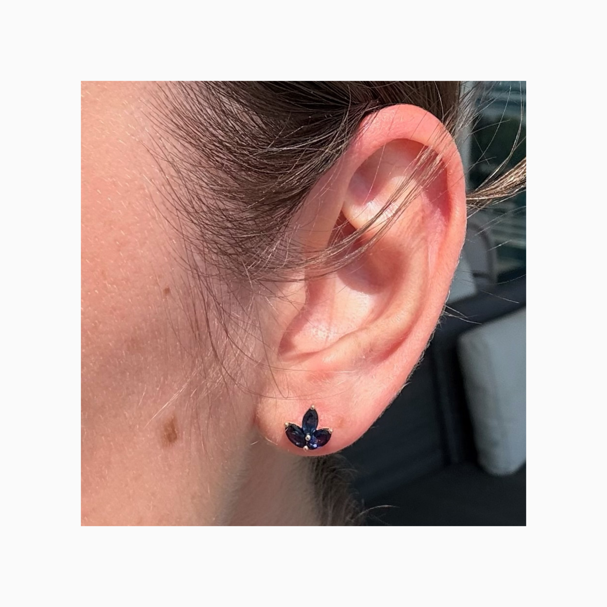 Petite 14K yellow gold marquise blue sapphire petal stud earring worn on ear