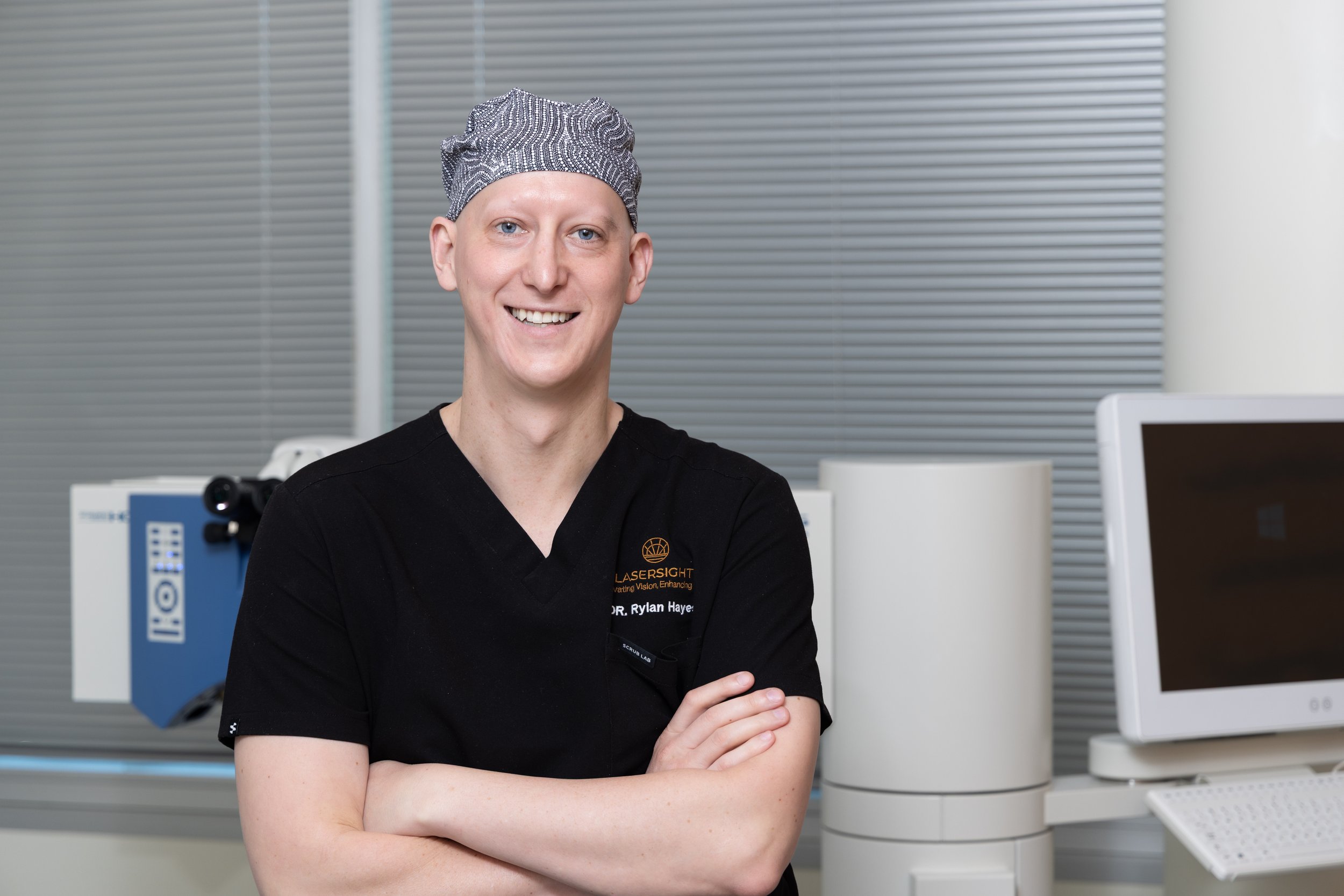 Dr Rylan Hayes - The Vision Surgeon in clinical scrubs and theatre hat.