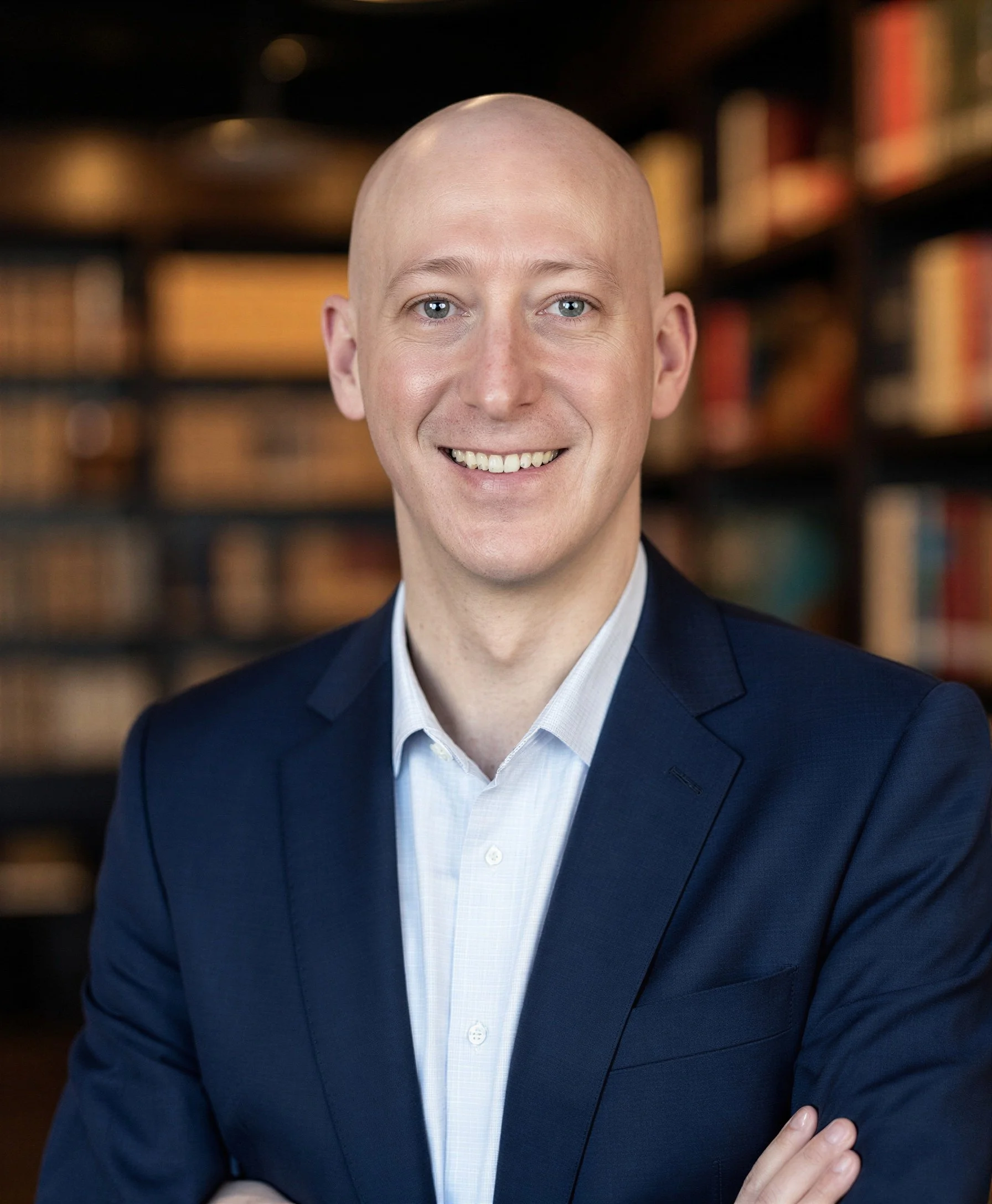 Portrait of Dr Rylan Hayes in a suit in front of a bookcase