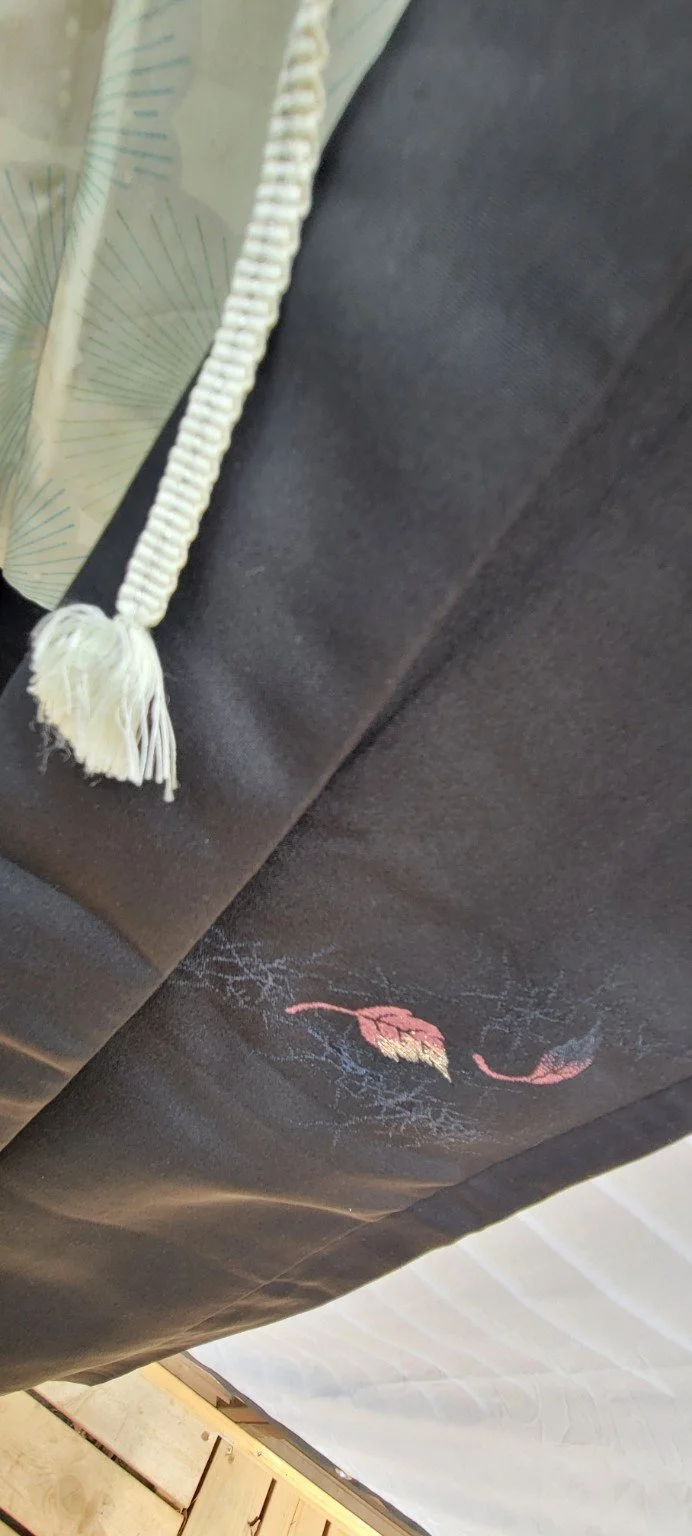 Subtle colored leaf detail beside original haori tie on black Japanese silk