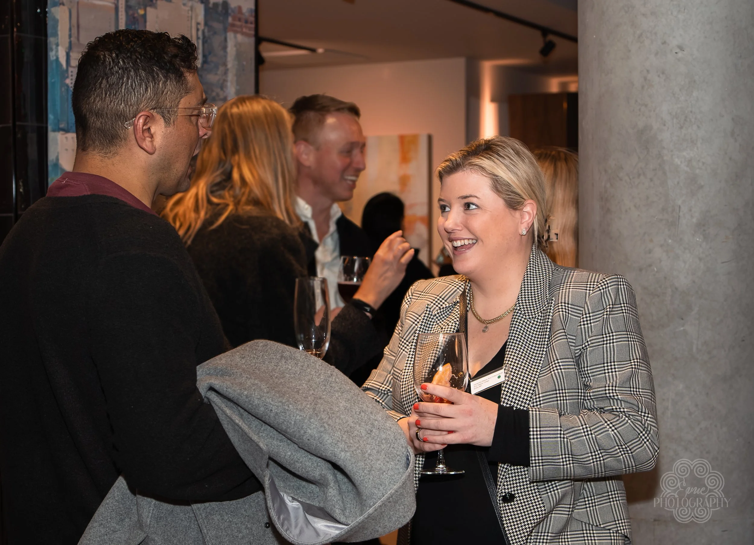 Group of people at a social gathering, some holding drinks, engaging in conversation