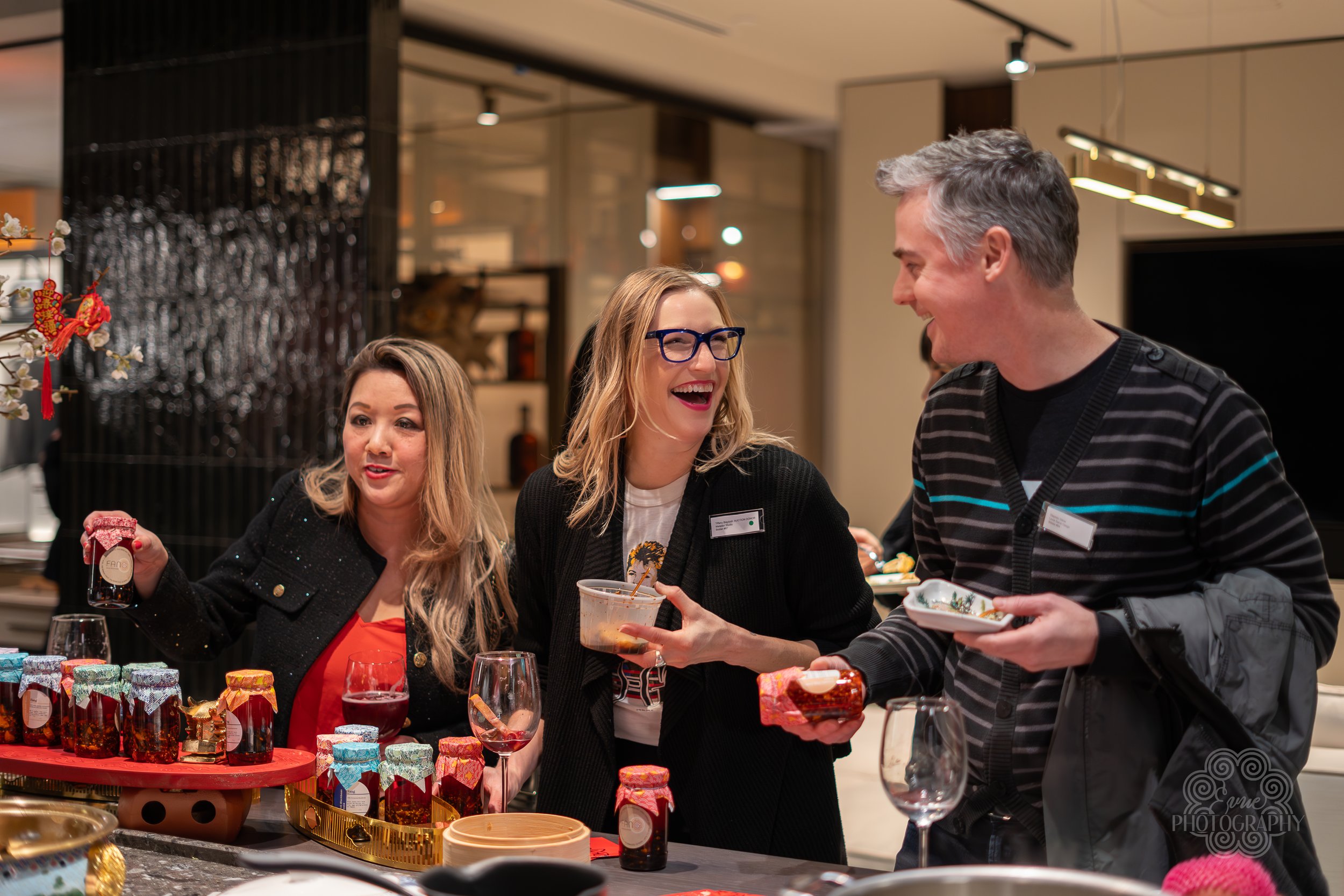 People celebrating at a holiday gathering, exchanging gifts and enjoying food and drinks at a decorated table.