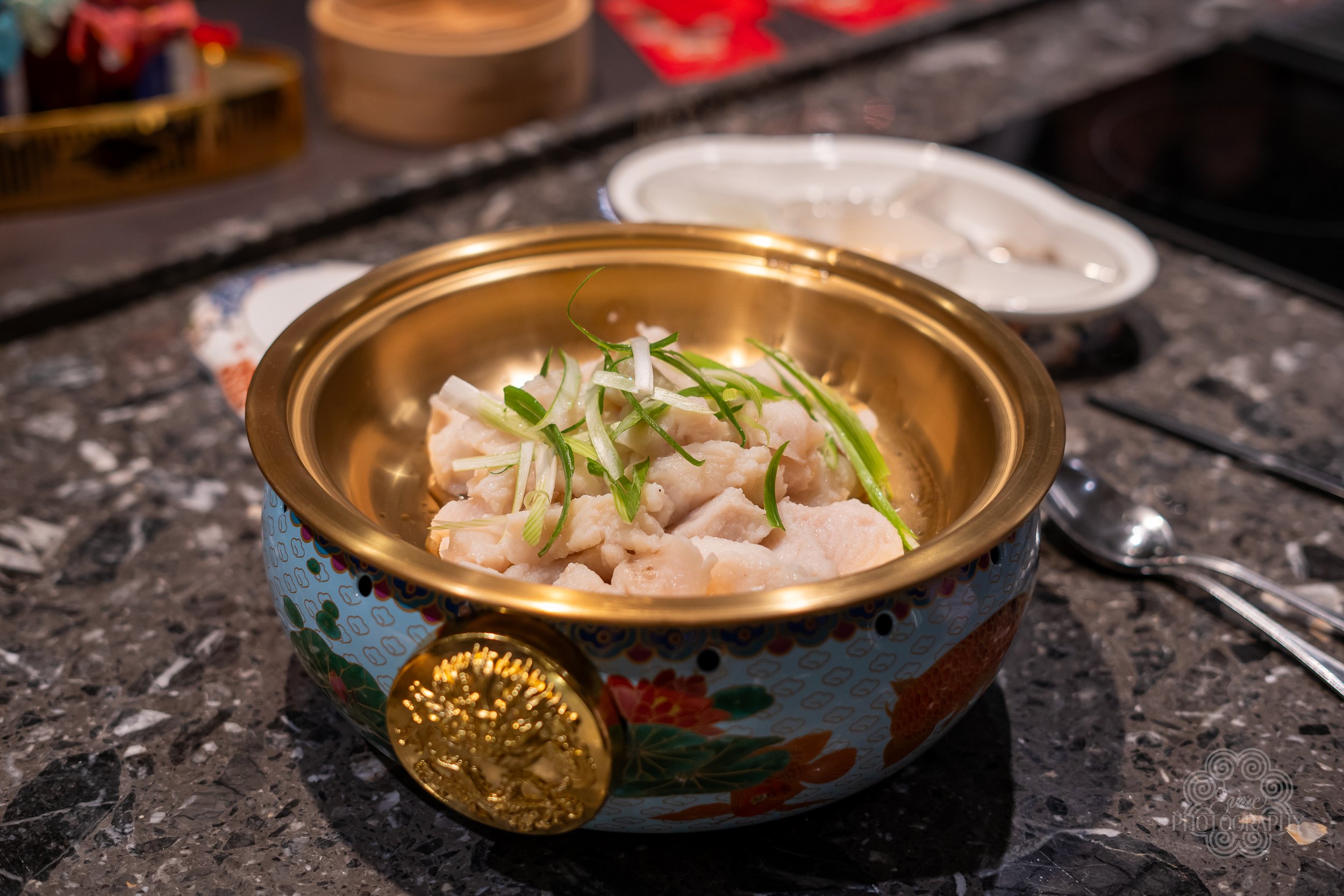 A bowl of chopped raw fish garnished with green onion on a kitchen counter.