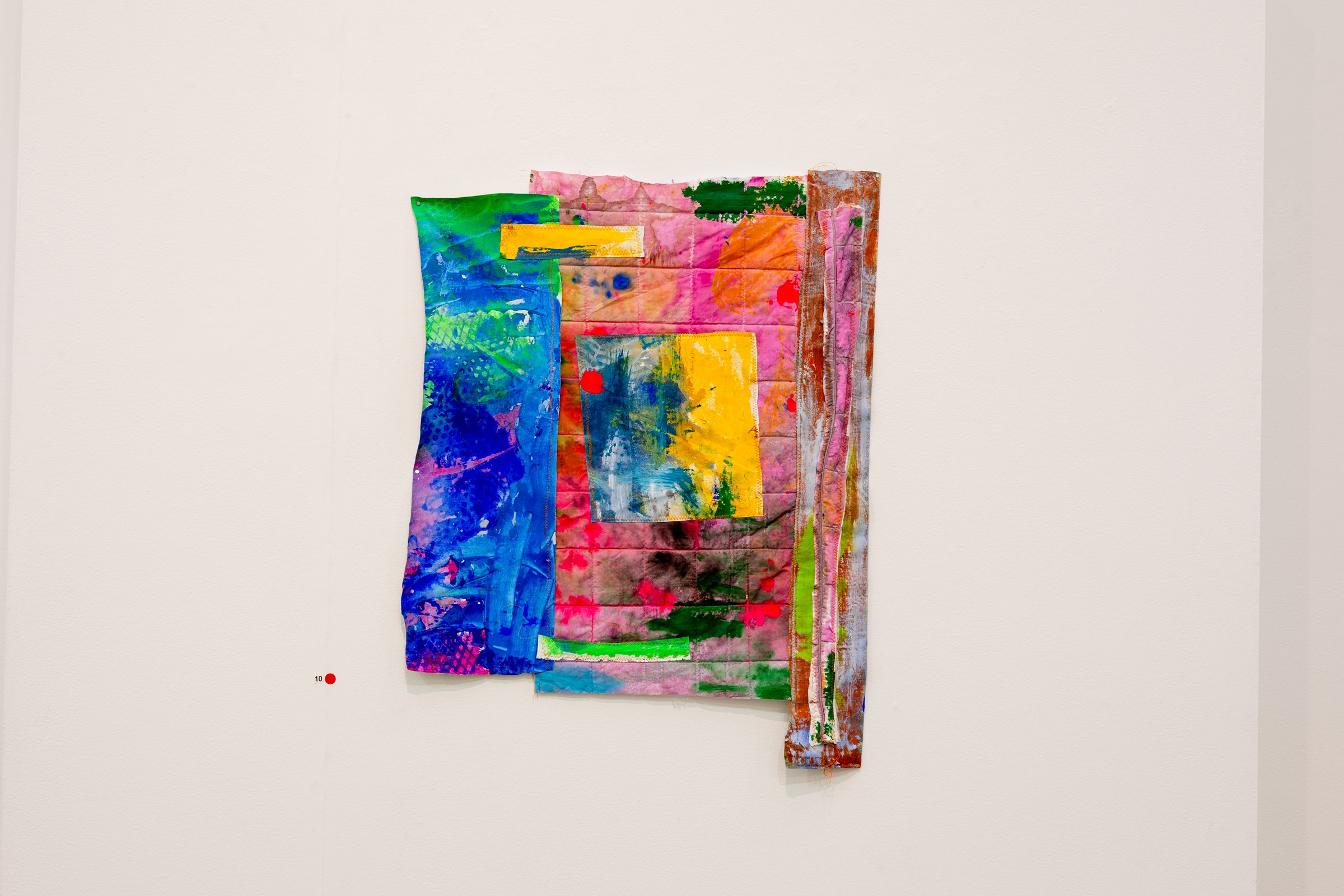Colorful abstract mixed-media artwork mounted on a white wall.