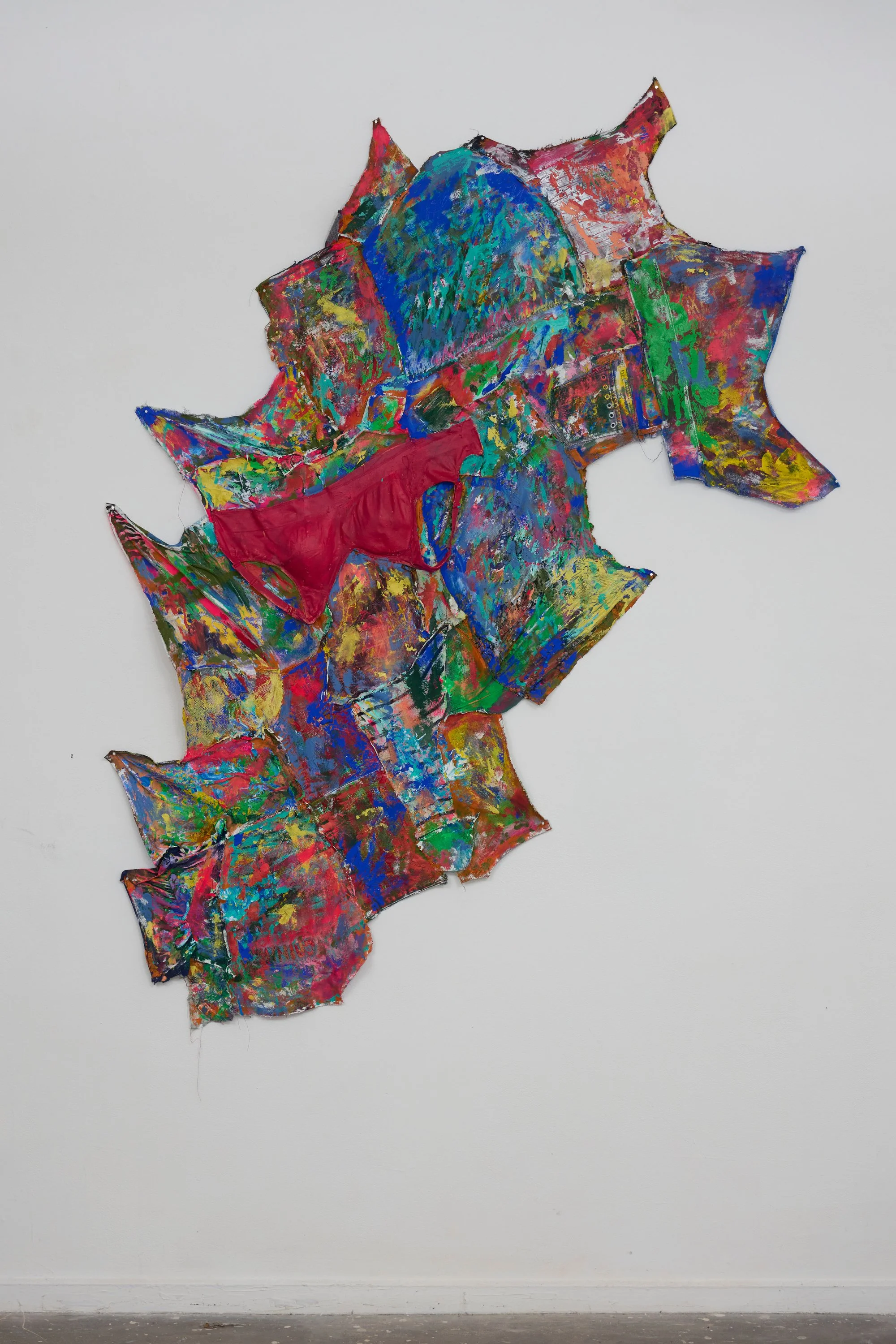 Colorful abstract mixed media art piece on a white wall with crumpled, layered textures.