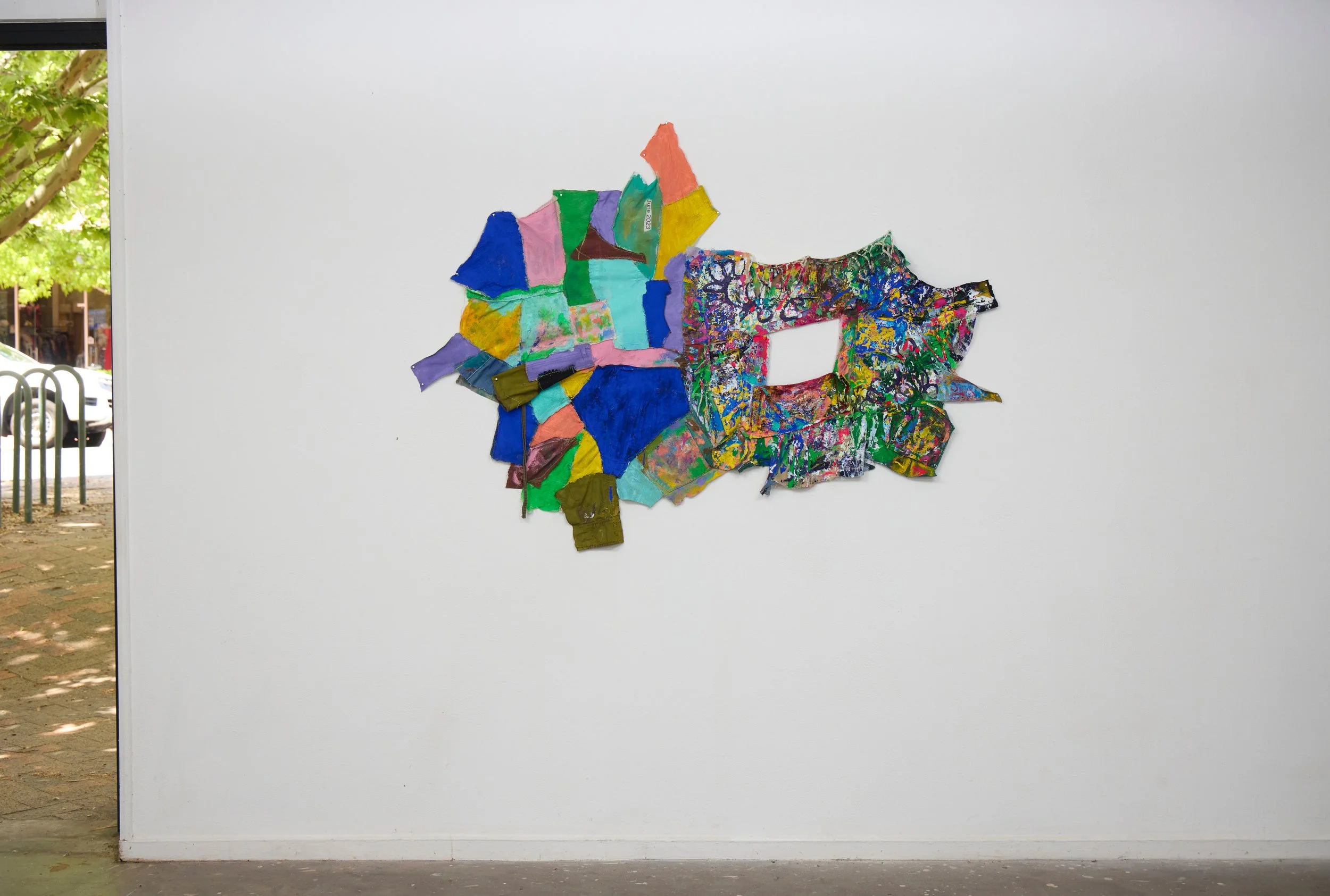 Colorful mixed media wall art on a white wall, occupying center space.