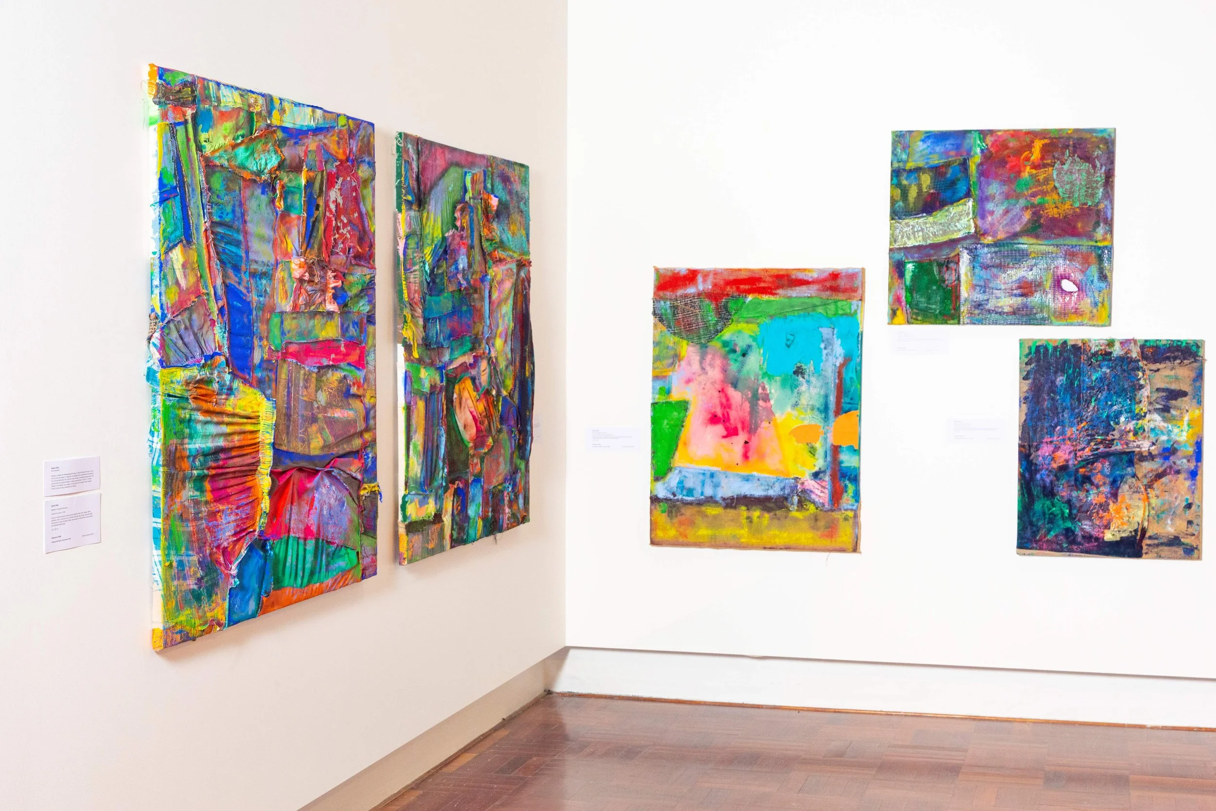 Colorful abstract paintings displayed on white gallery walls.