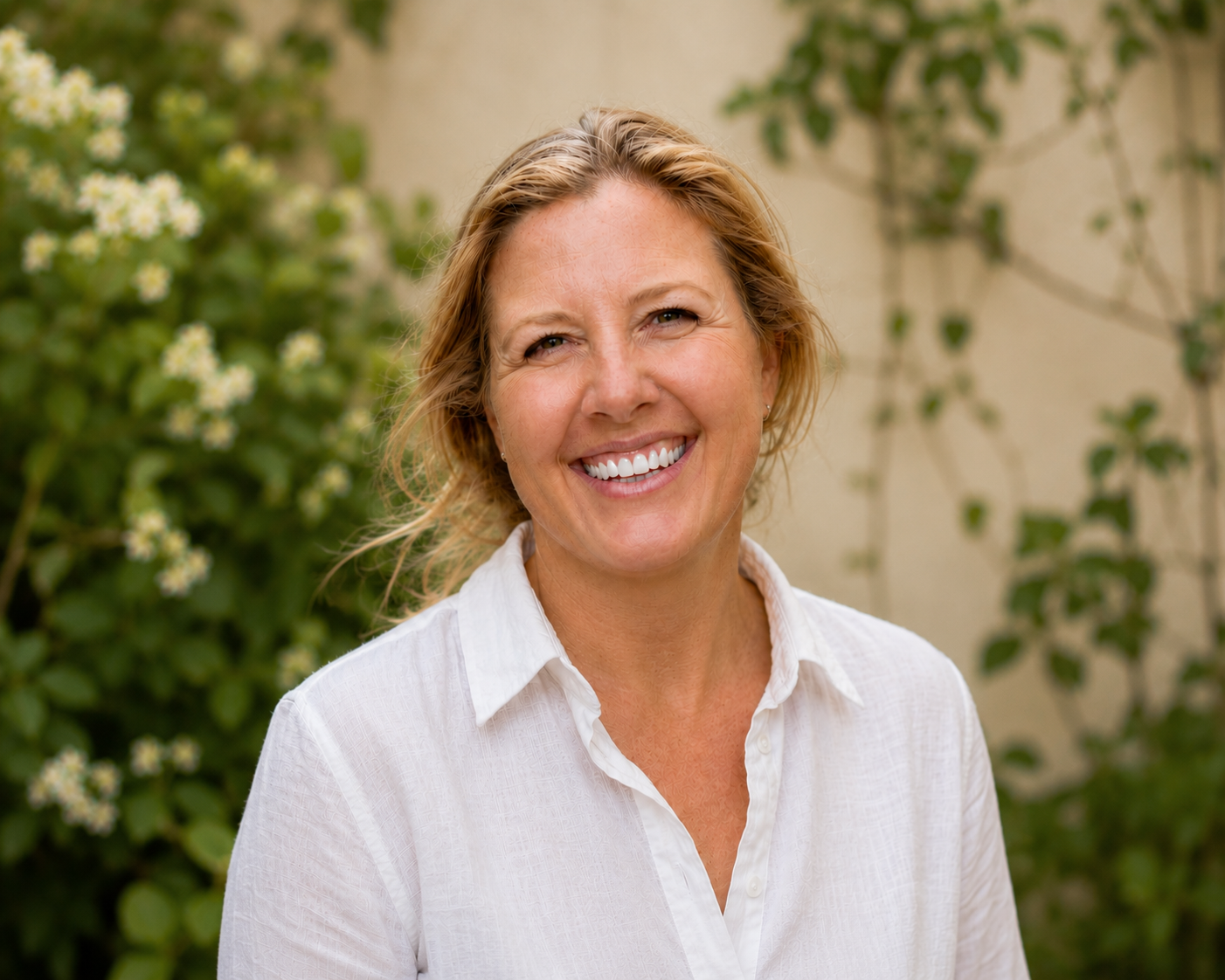 Alicia Halls, counsellor, smiling outdoors in a white shirt with greenery in the background.