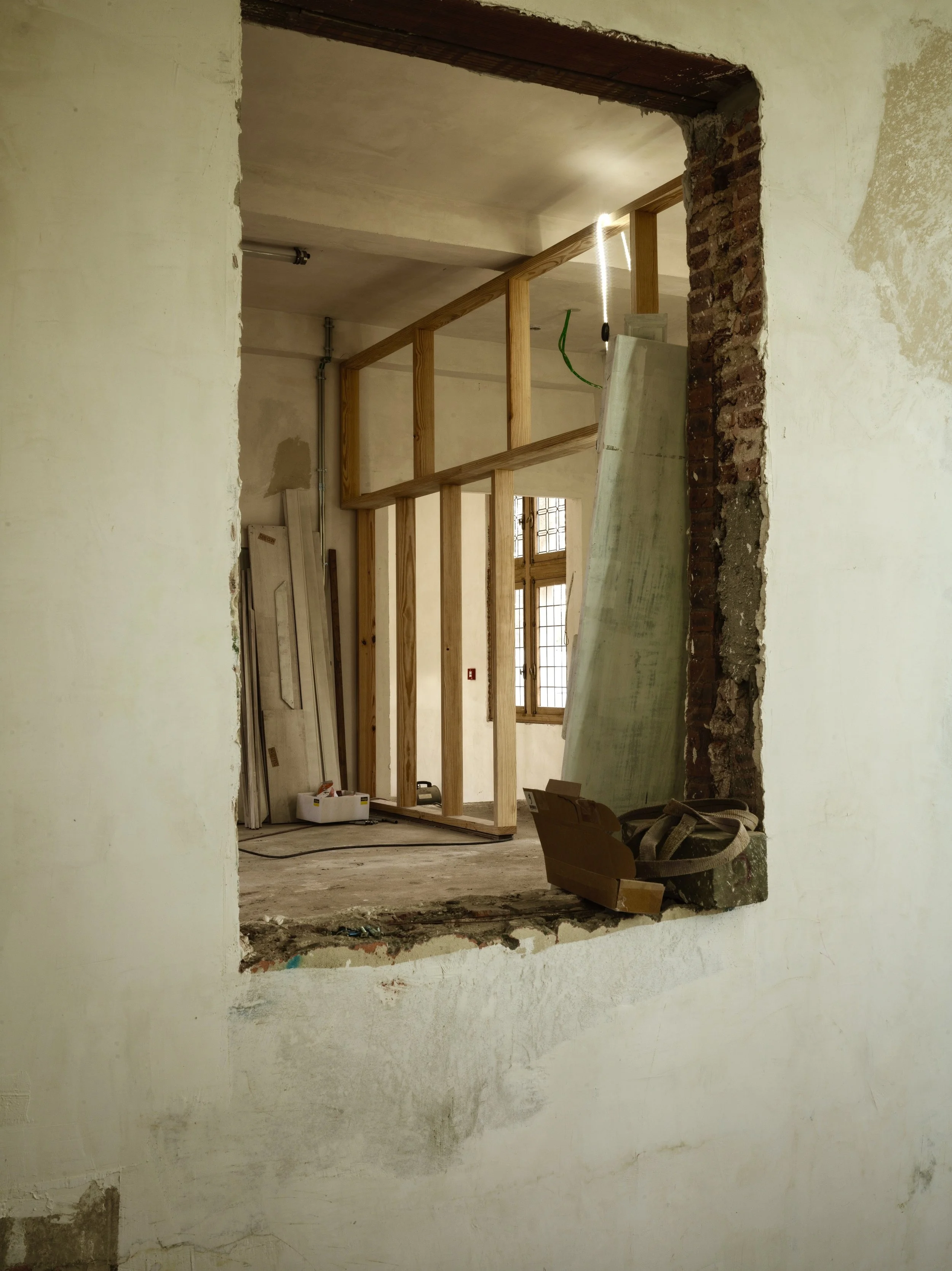 Construction of an interior wall with exposed wooden framing inside a building under renovation.