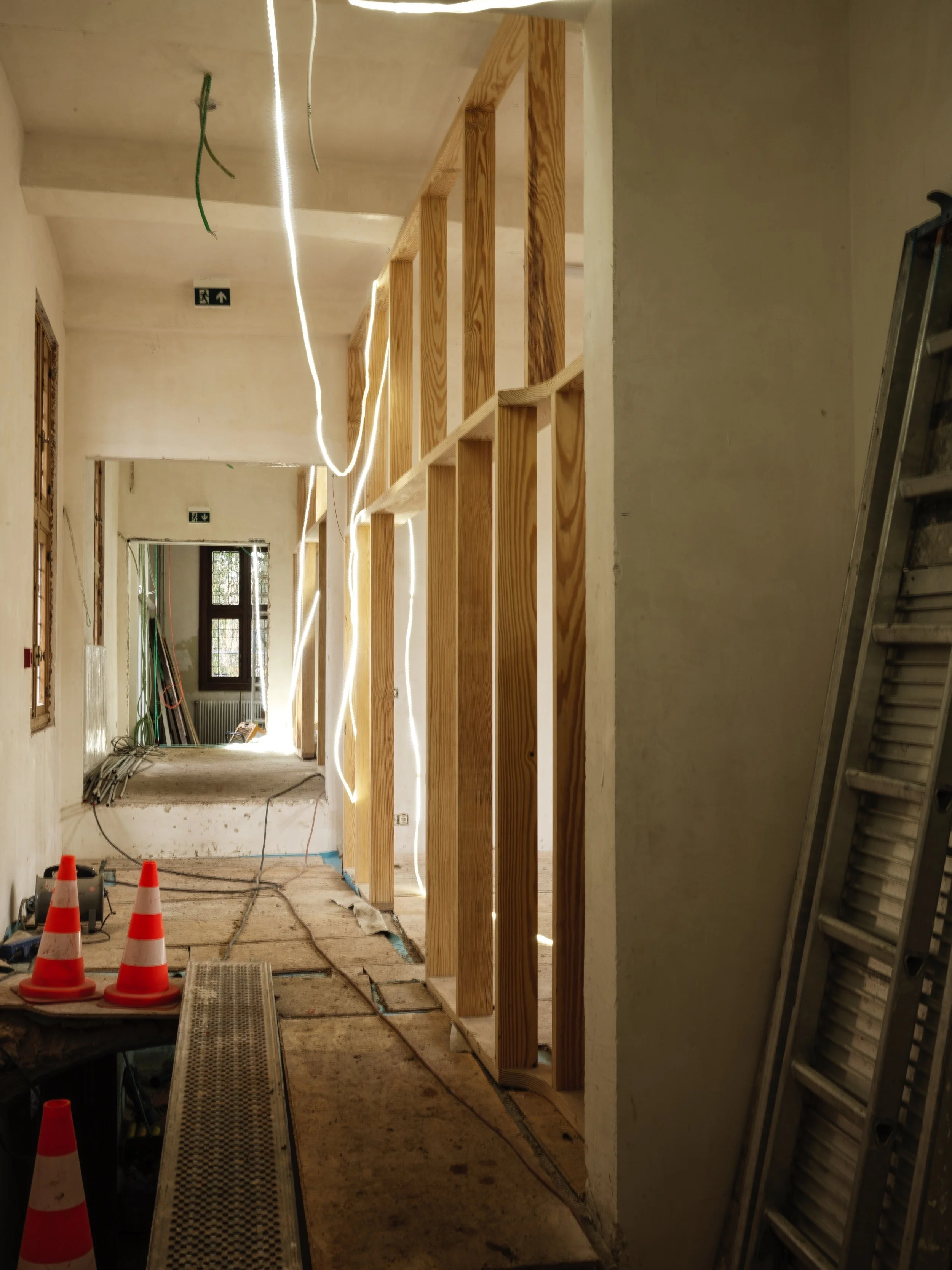 Construction site with wooden framing, construction signs, and orange cones.
