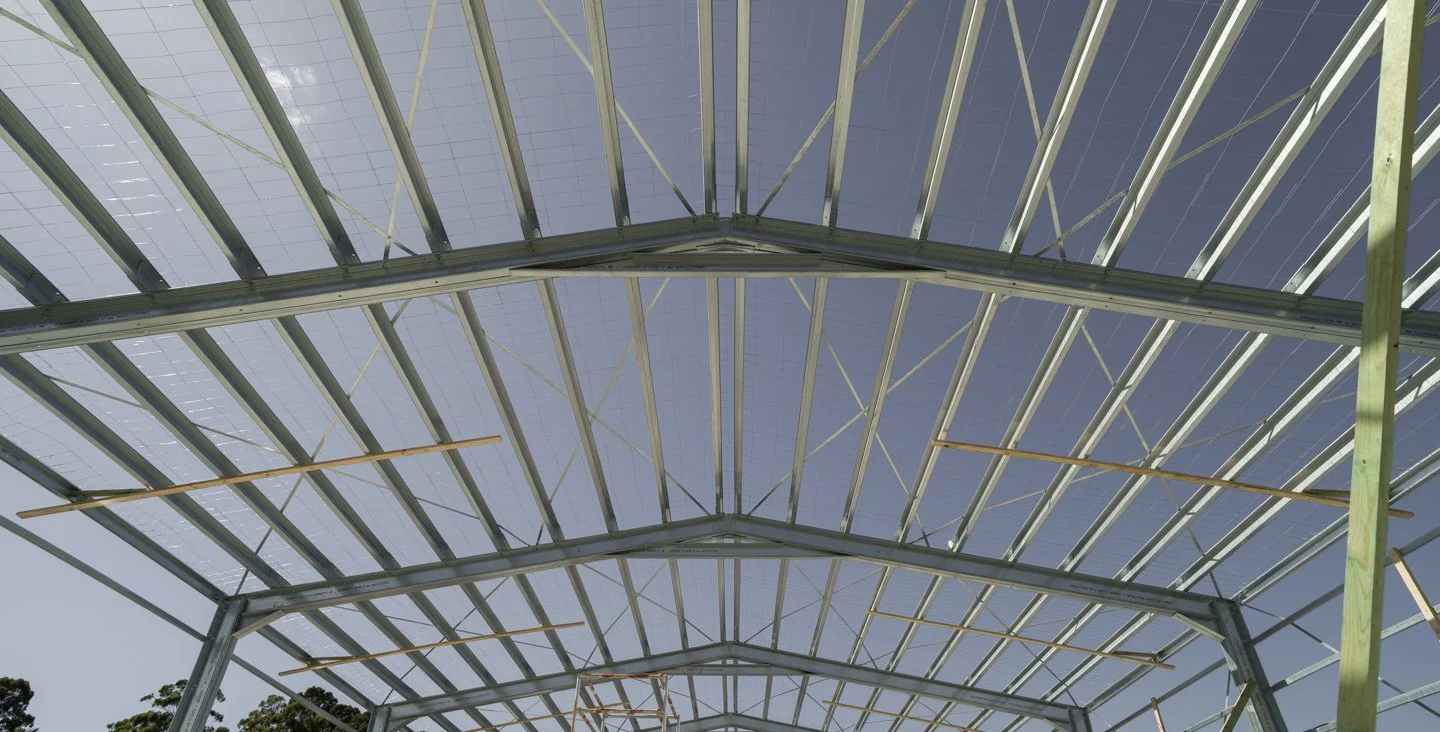 Under construction greenhouse frame with solar panels installed on the roof.