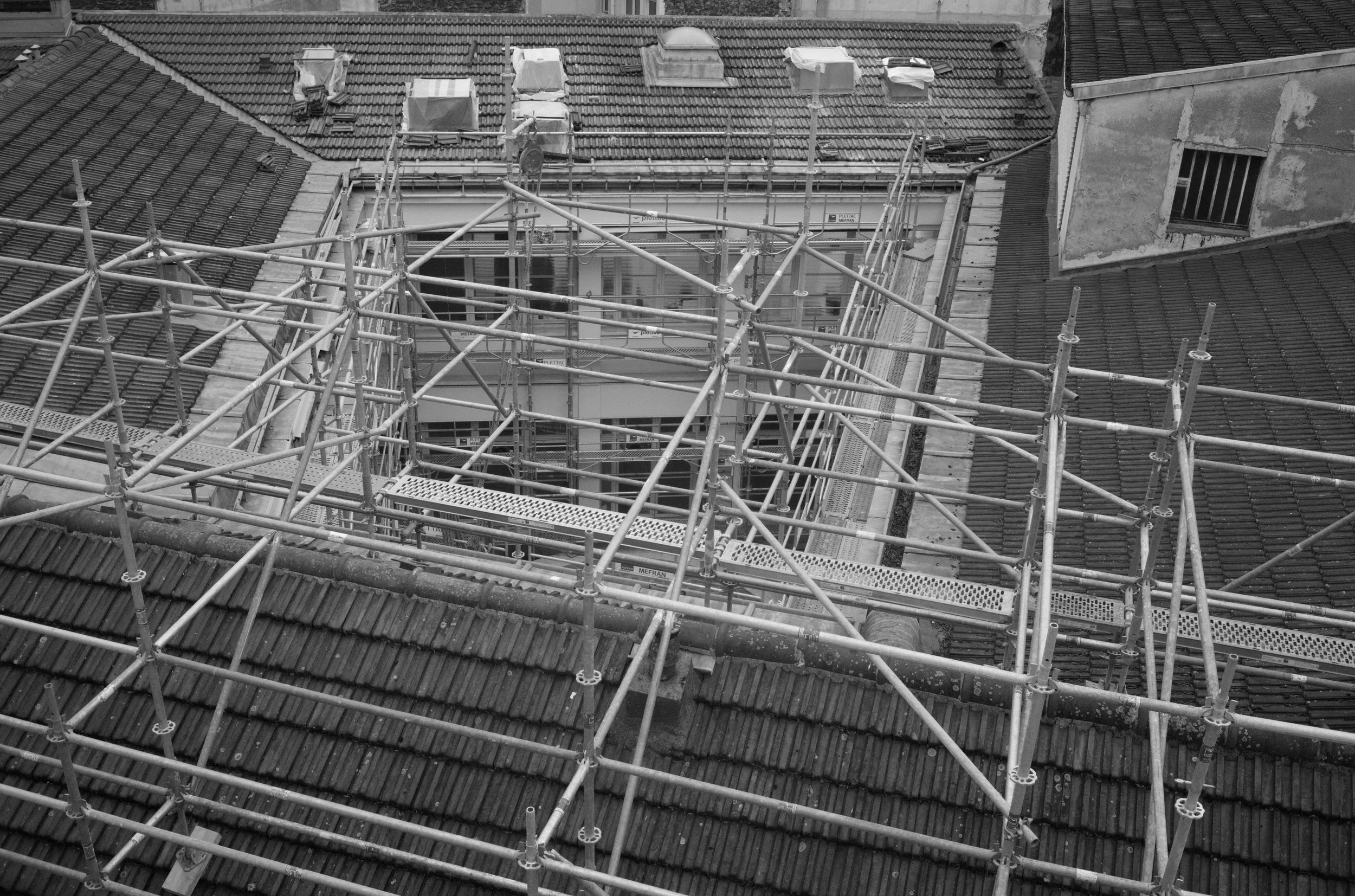 Overhead view of dense metal scaffolding erected over a traditional pitched tile roof.