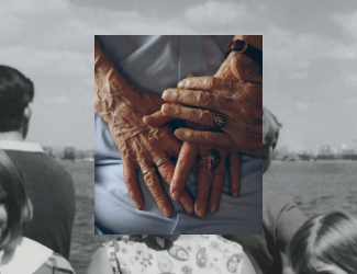 Close-up of elderly hands intertwined, showing signs of aging and wearing a ring and a watch.