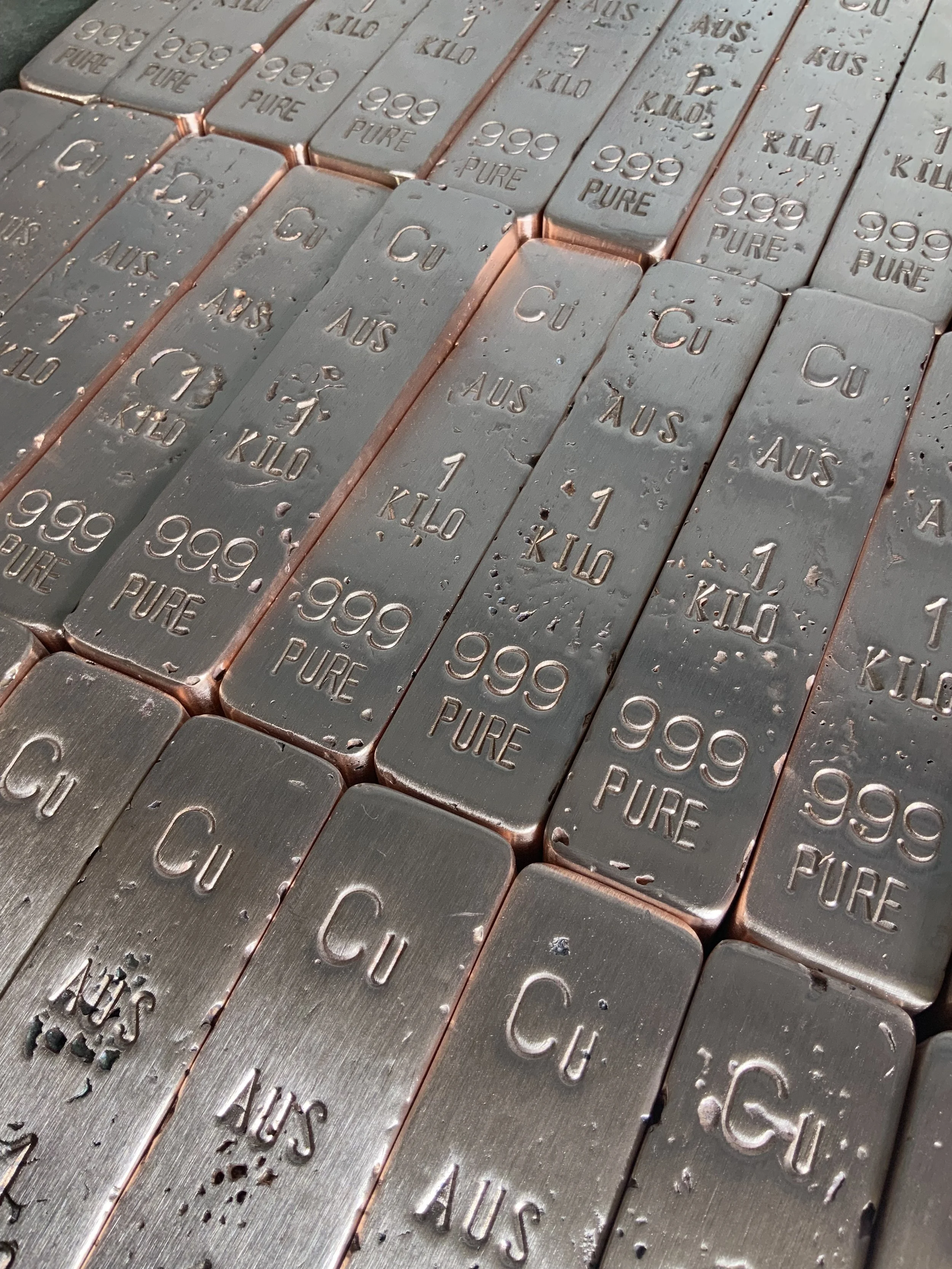 Multiple stacked copper bullion bars 999 fine arranged in rows Hinterland Bullion Co