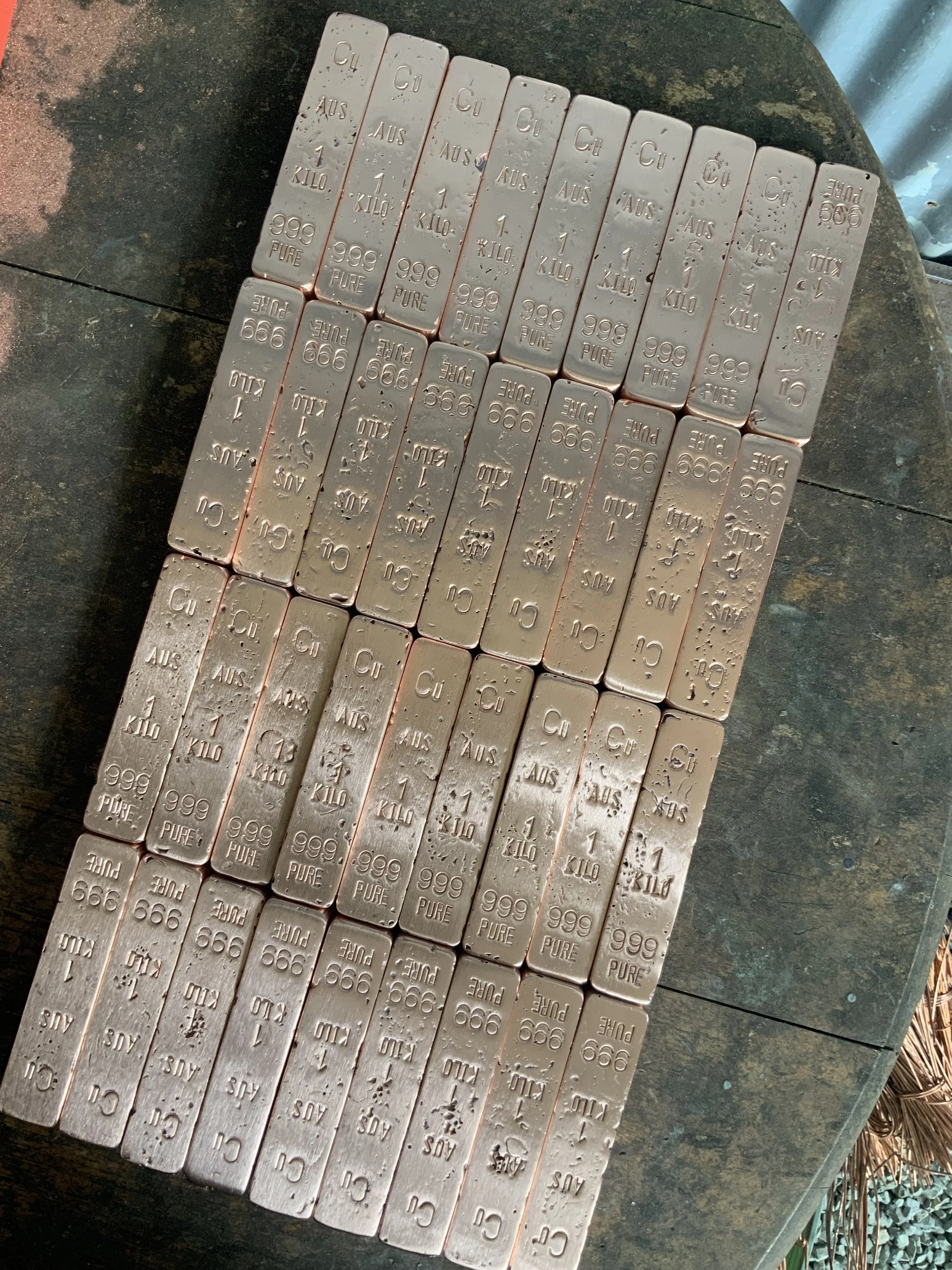 Multiple stacked copper bullion bars 999 fine arranged in rows Hinterland Bullion Co