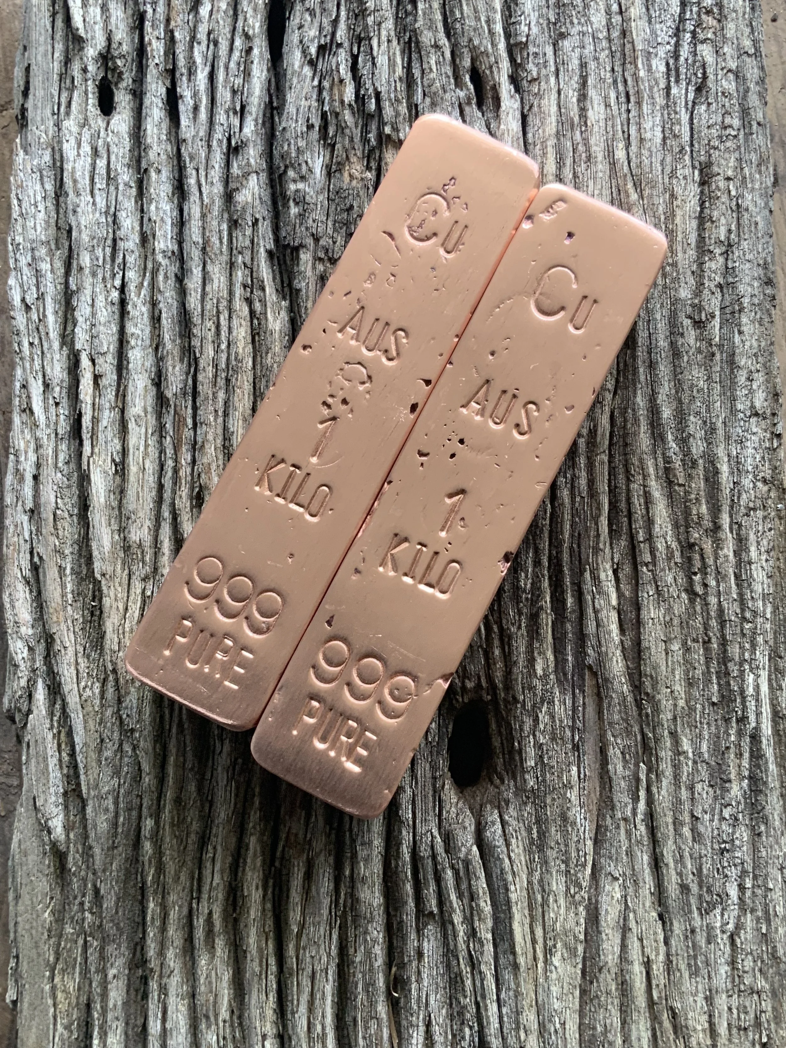 Two 1kg copper bullion bars 999 fine resting on wood surface Australia