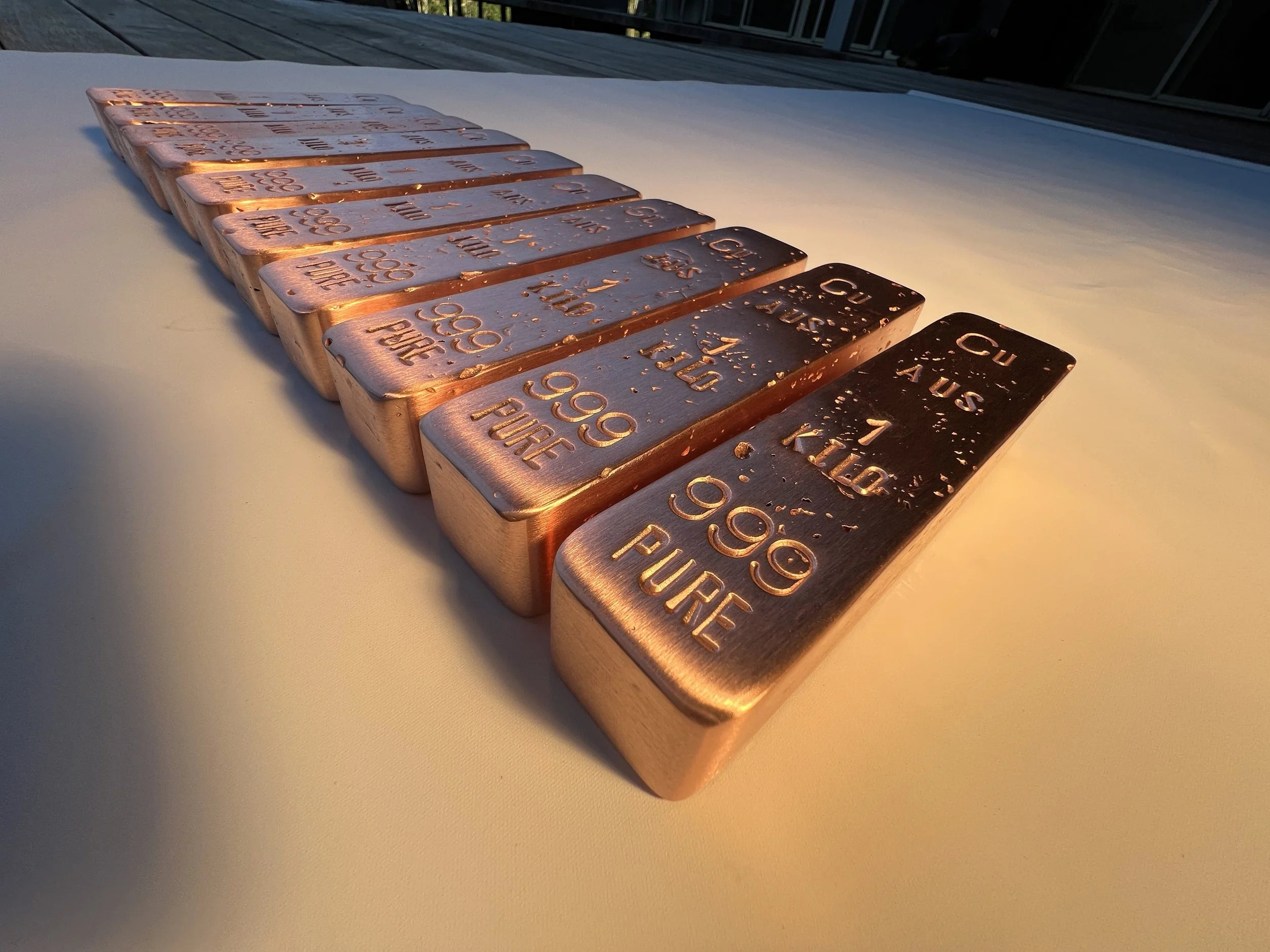 Row of 1kg copper bullion bars 999 fine arranged in line Hinterland Bullion Co