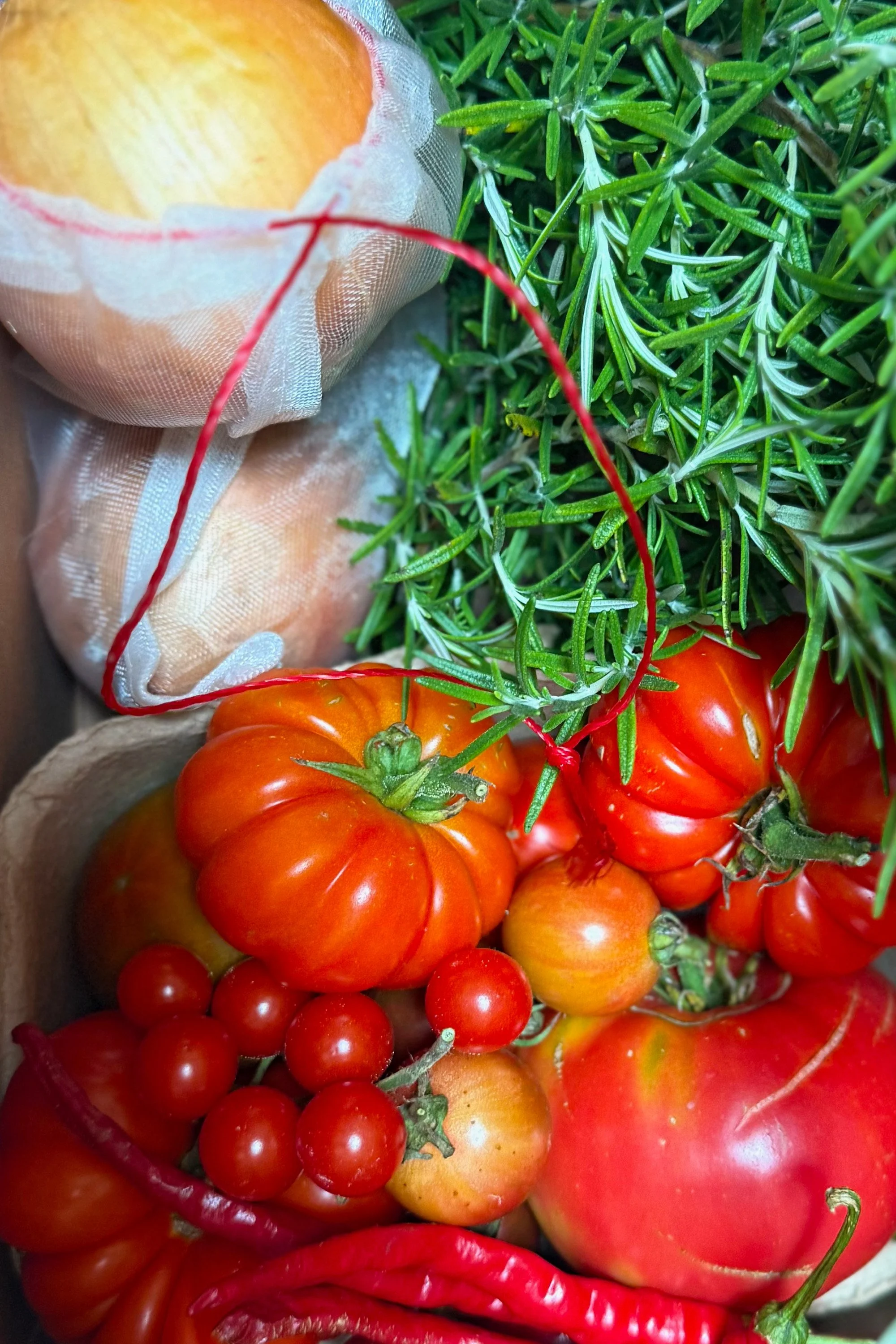 Ribbed heirloom and cherry tomatoes beside fresh-cut rosemary in The Heirloom Stack Wild Kit, Pandemonium Gardens