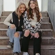 Two young women sitting on outdoor stairs, smiling at the camera.