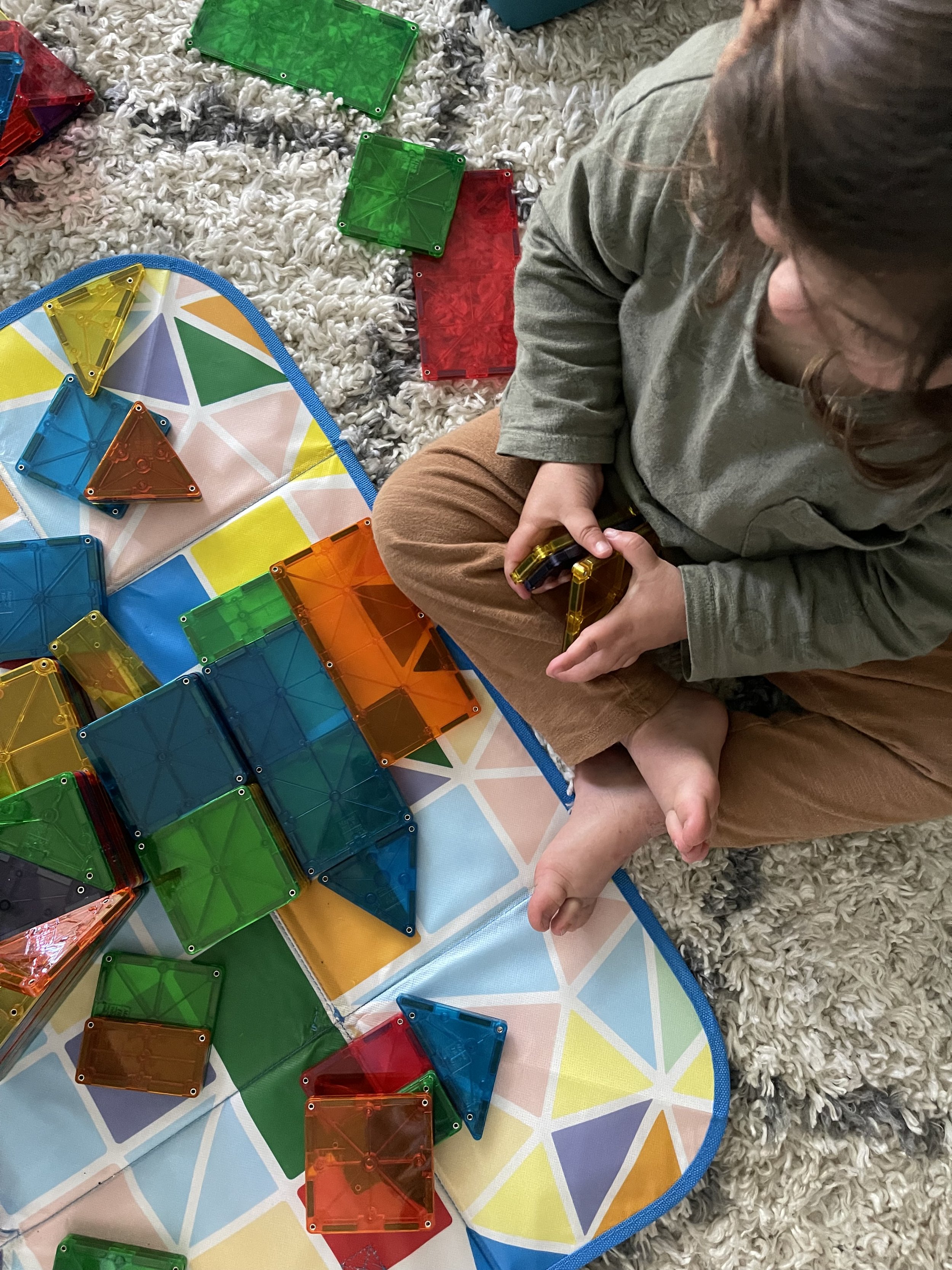 a toddler playing with magnetic tiles