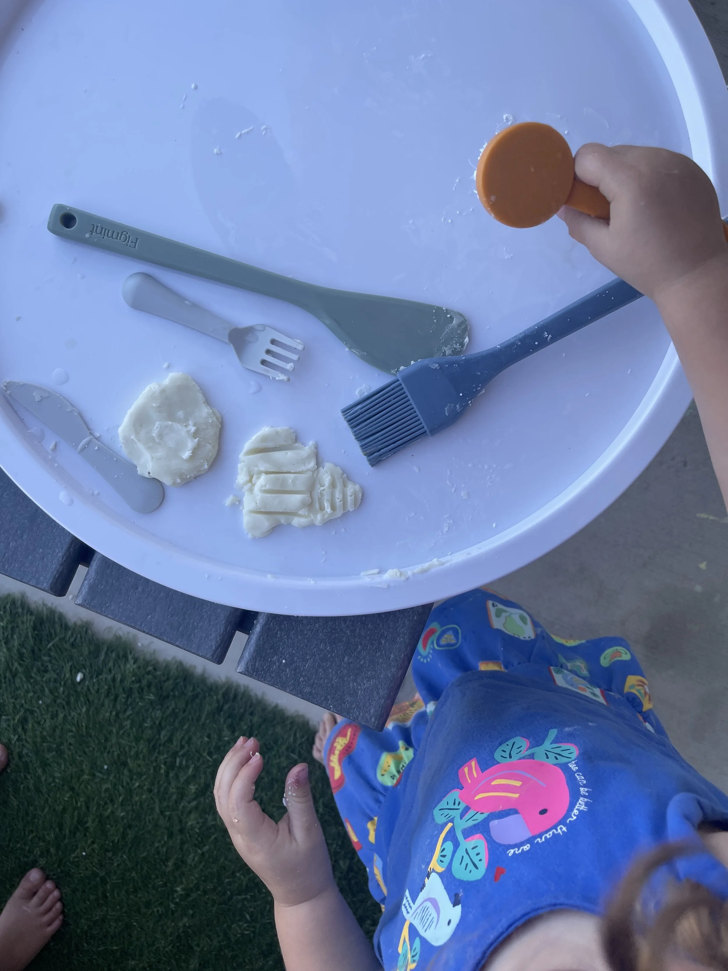 Child molding and texturing dough with a fork and basting brush during open-ended sensory play