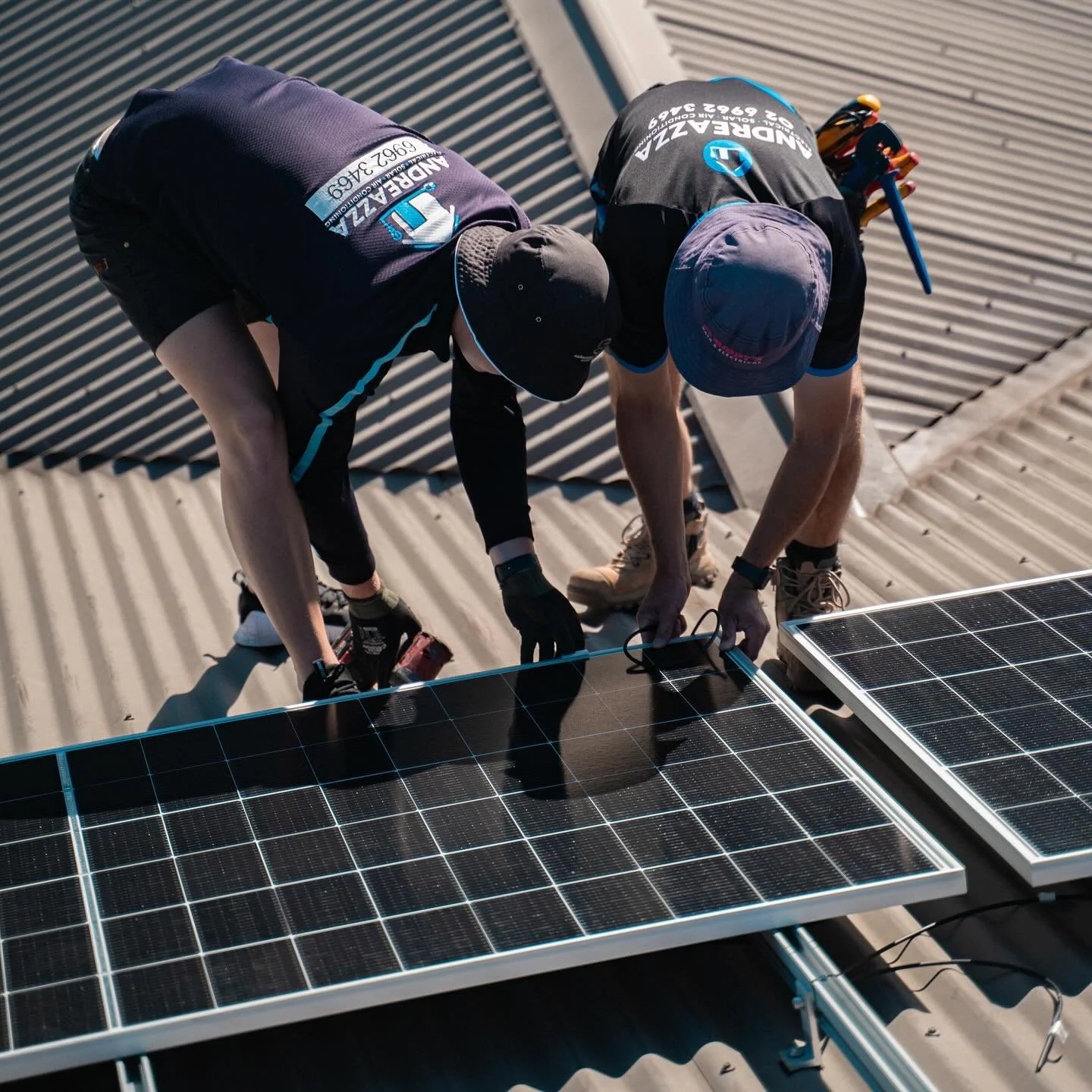Two workers installing or maintaining solar panels on a rooftop.