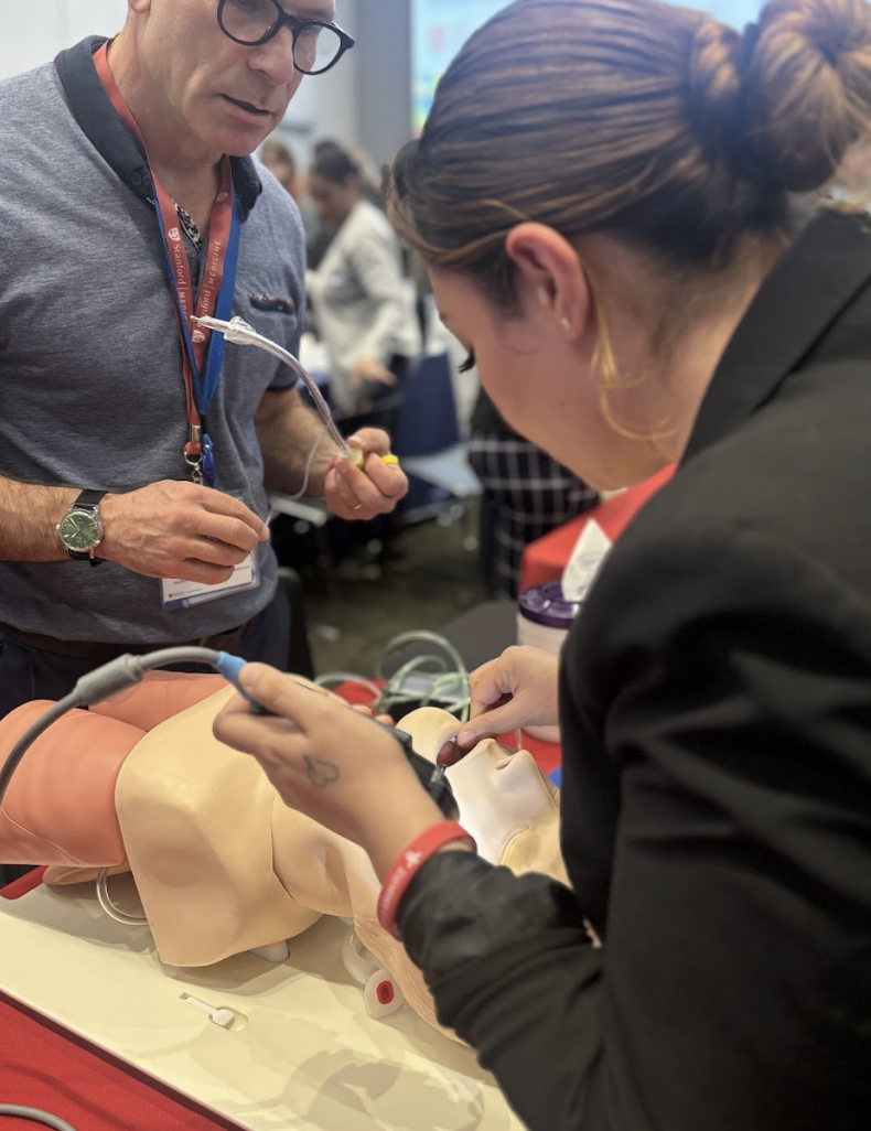 Two individuals practicing medical procedures on a medical mannequin in an educational setting.