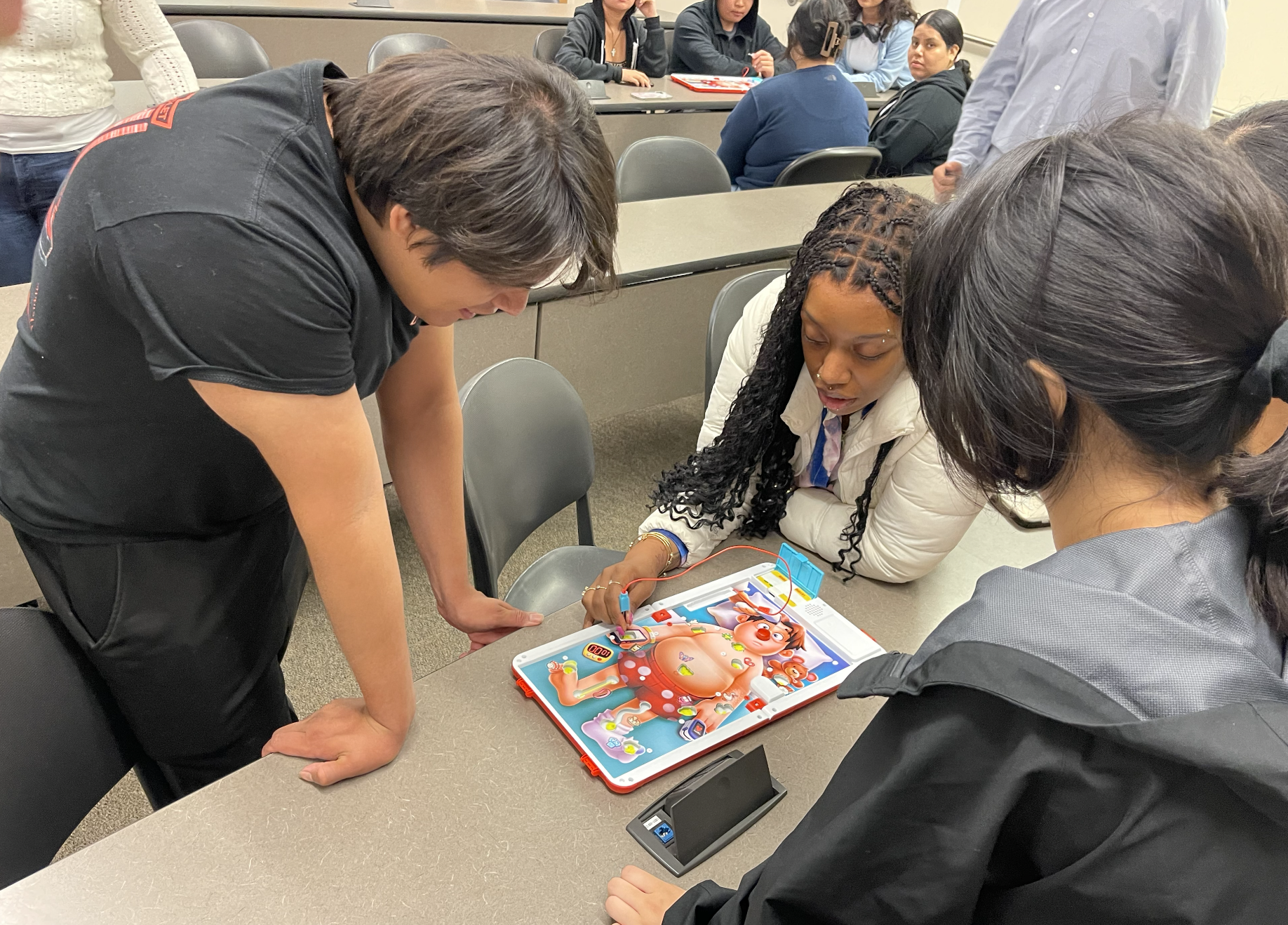 Three people, two women and one man, gathered around a table playing a board game that features a pig princess and other colorful characters.