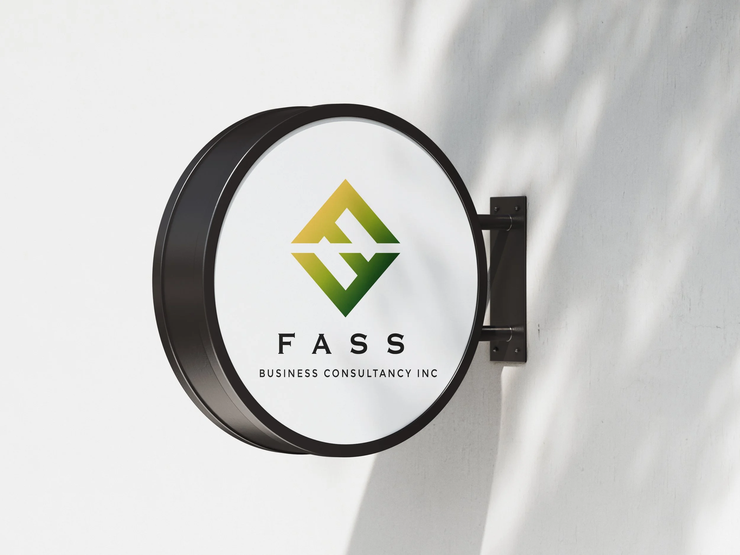 Round black sign with the logo and text for FASS Business Consultancy Inc mounted on a white wall.