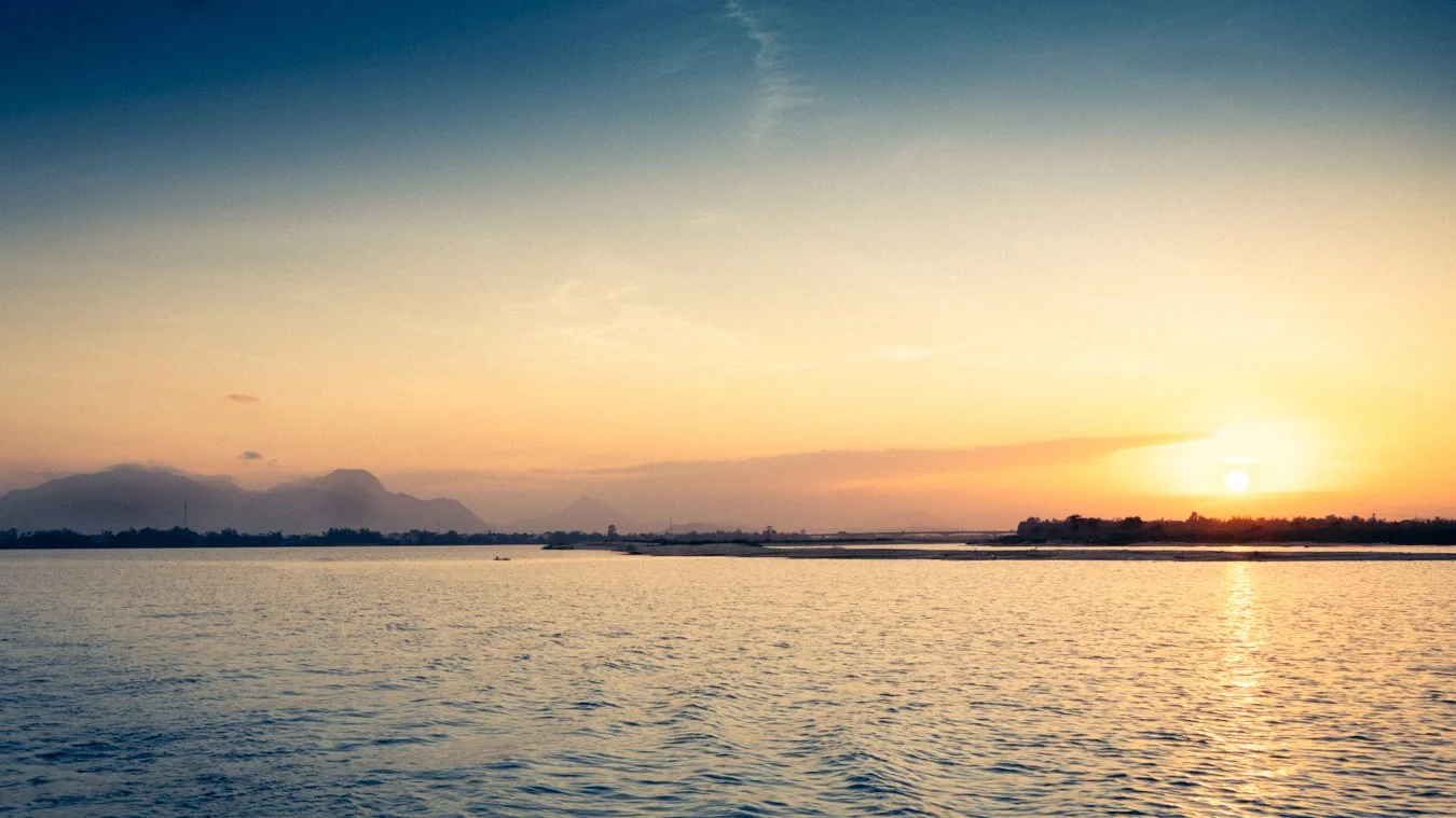 Sunset over a body of water with a mountain range in the distance