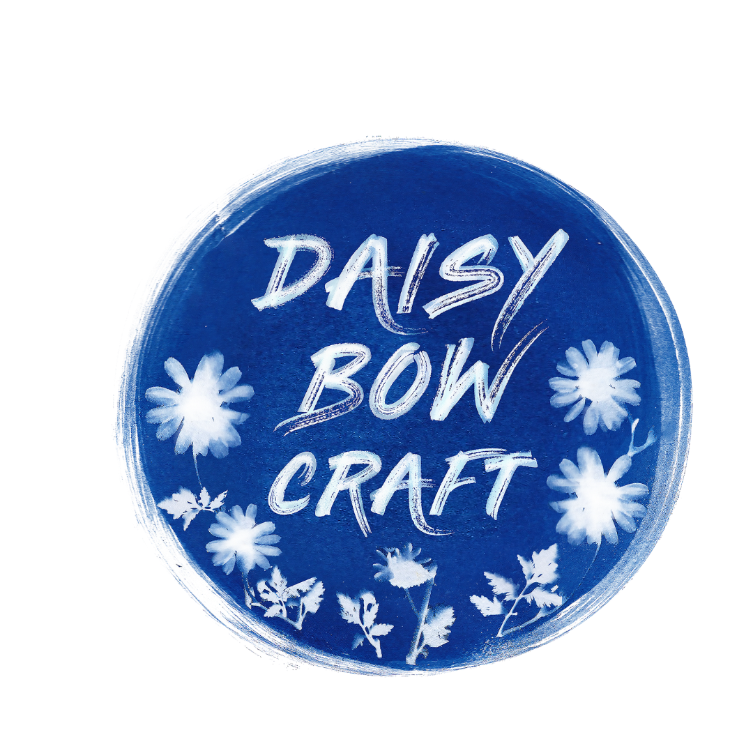 Daisy Bow Craft logo featuring the organisation name in white brush-script on a deep blue circular background surrounded by cyanotype-style illustrations of daisies and botanical foliage