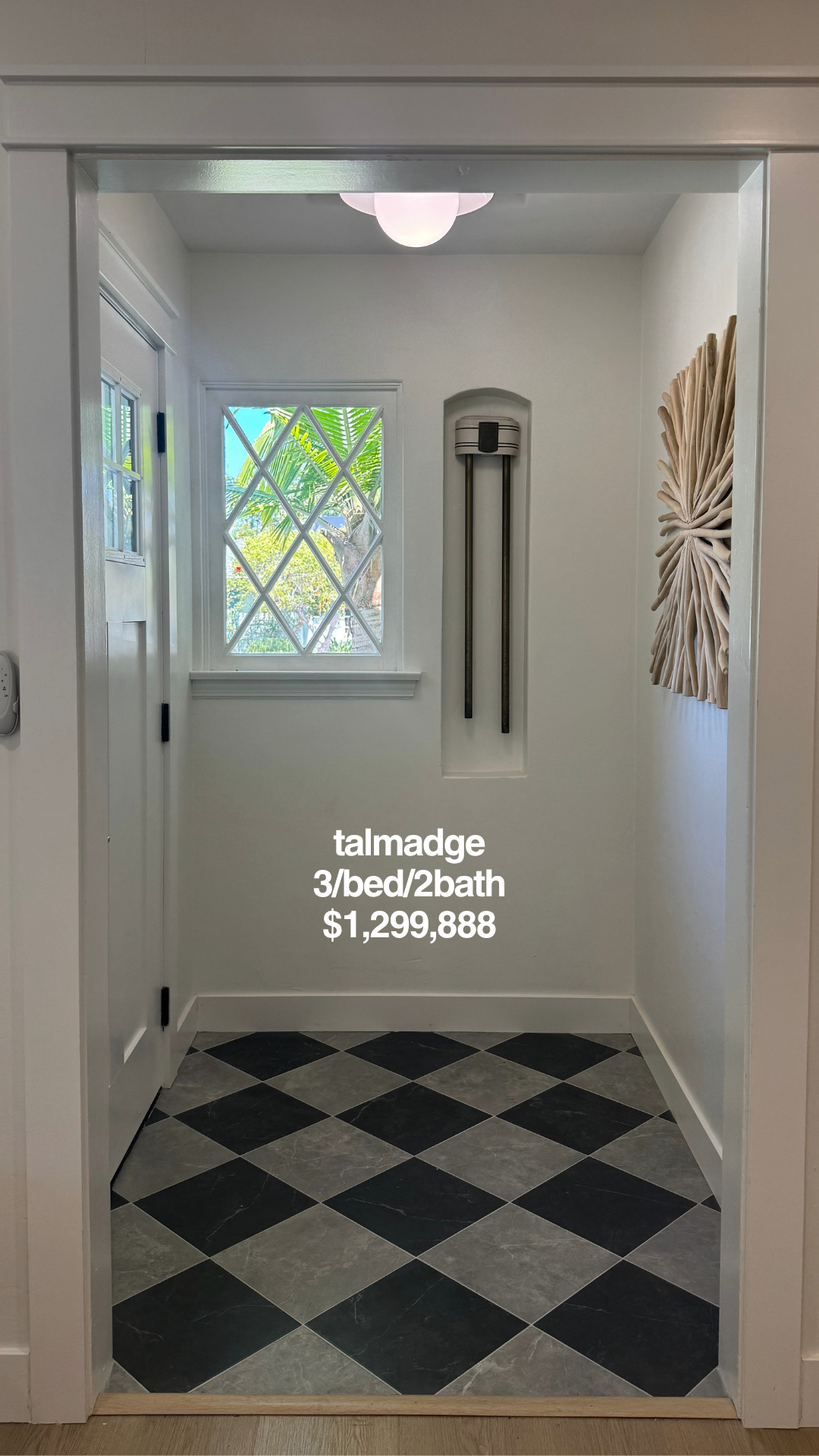 Interior view of a small lobby or entryway with a window showing tropical plants outside. Decor includes a wall art piece resembling a large leaf and a modern wall-mounted lamp. Text overlay indicates the listing for a home in Talmadge, with 3 bedrooms, 2 bathrooms, priced at $1,299,888.
