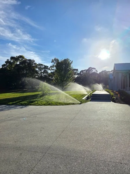 Concrete area leading to grass with watering system running