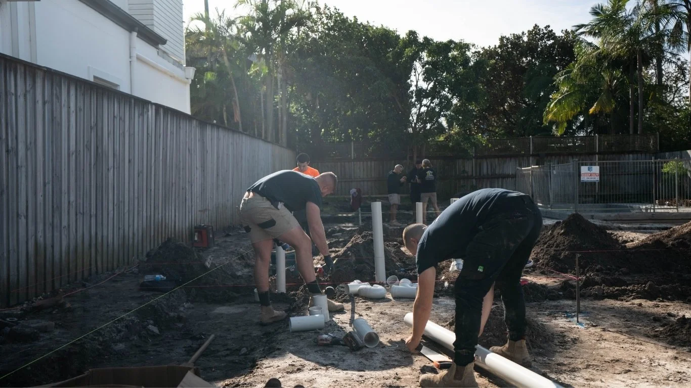 Construction workers installing underground pipes at a construction site during daylight.