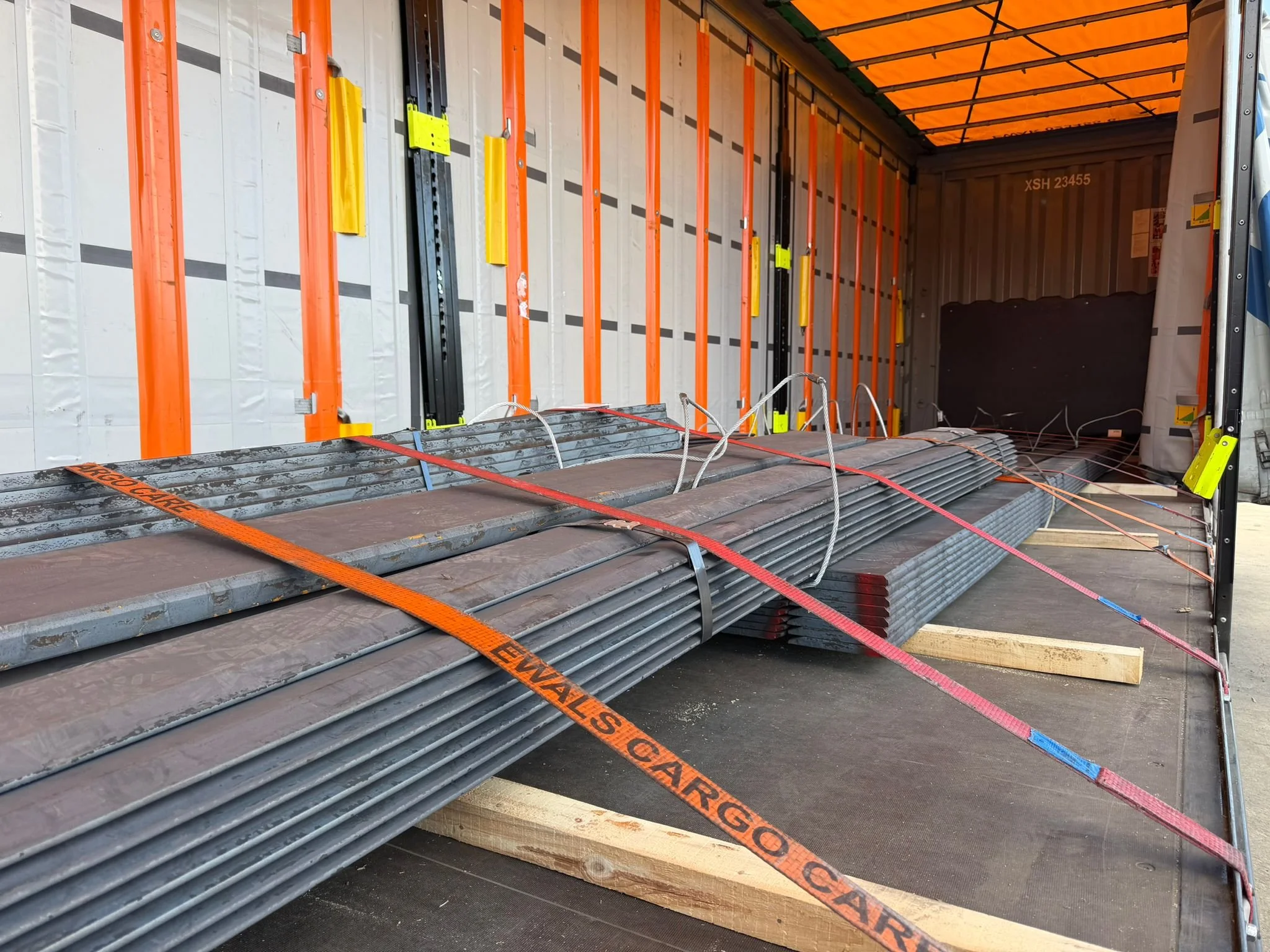 Steel pipes secured with cargo straps inside a moving truck.