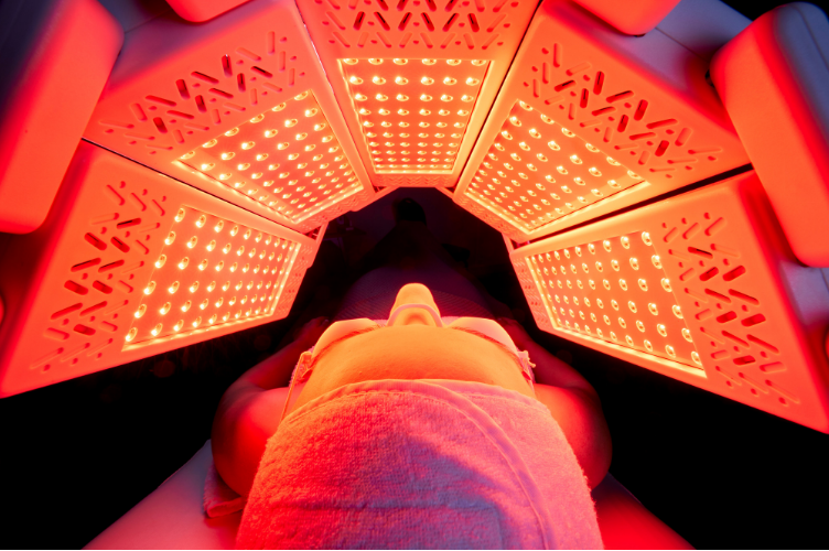 Person receiving red LED light therapy treatment inside a red LED light panel.