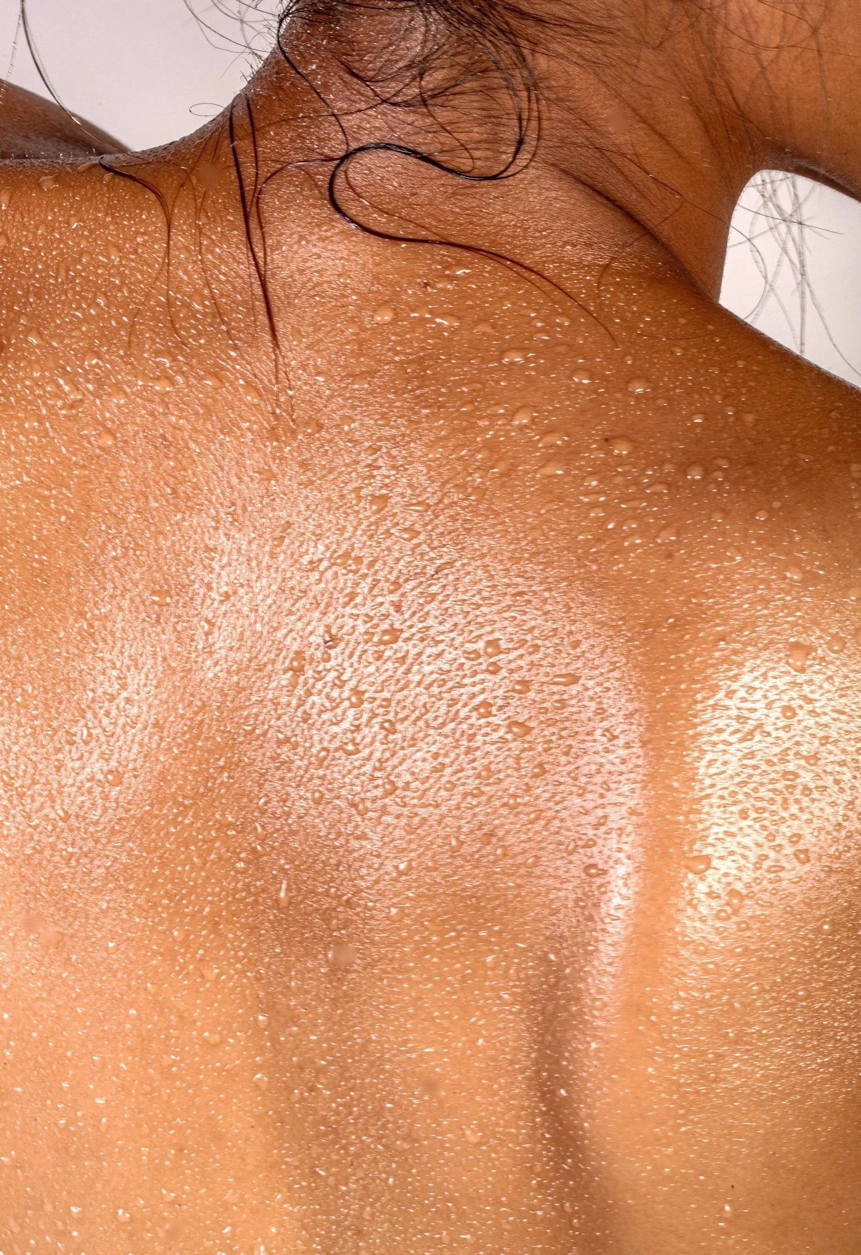 Close-up of a person's neck and shoulder area with water droplets on skin.