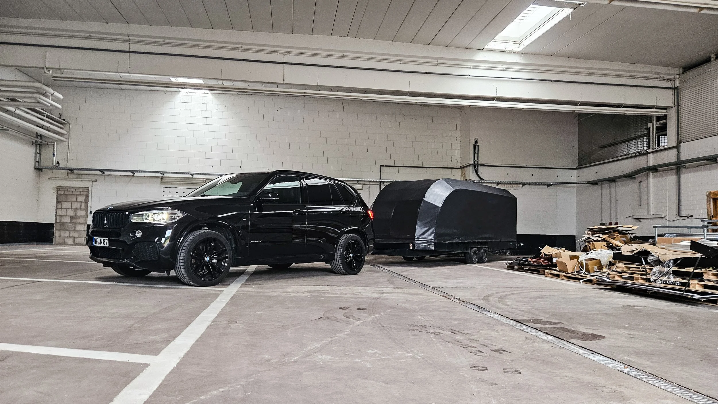 Ein schwarzer BMW X6 mit Anhänger in einer autostellhalle.