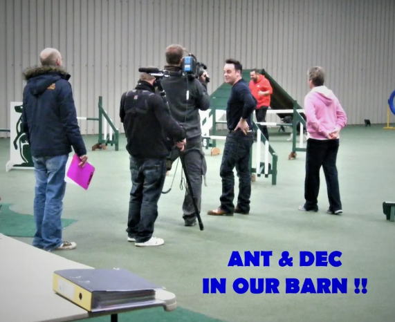 People in a barn, some with clipboards and camera equipment, engaging in a filming or interview session, with text saying 'ANT & DEC IN OUR BARN !!'