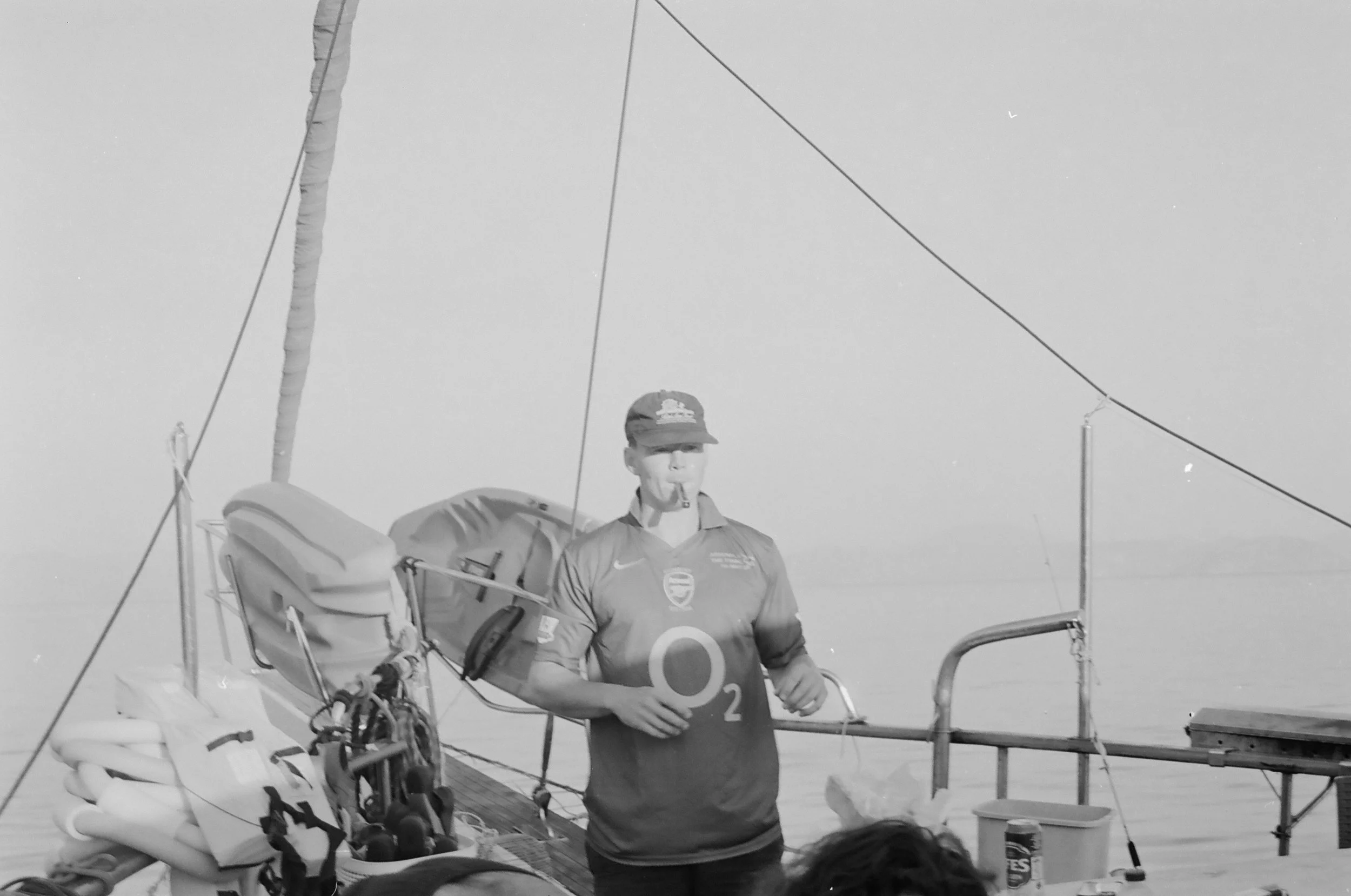 A woman in a sports jersey holding an oxygen tank, standing on a boat near a dock with water in the background.